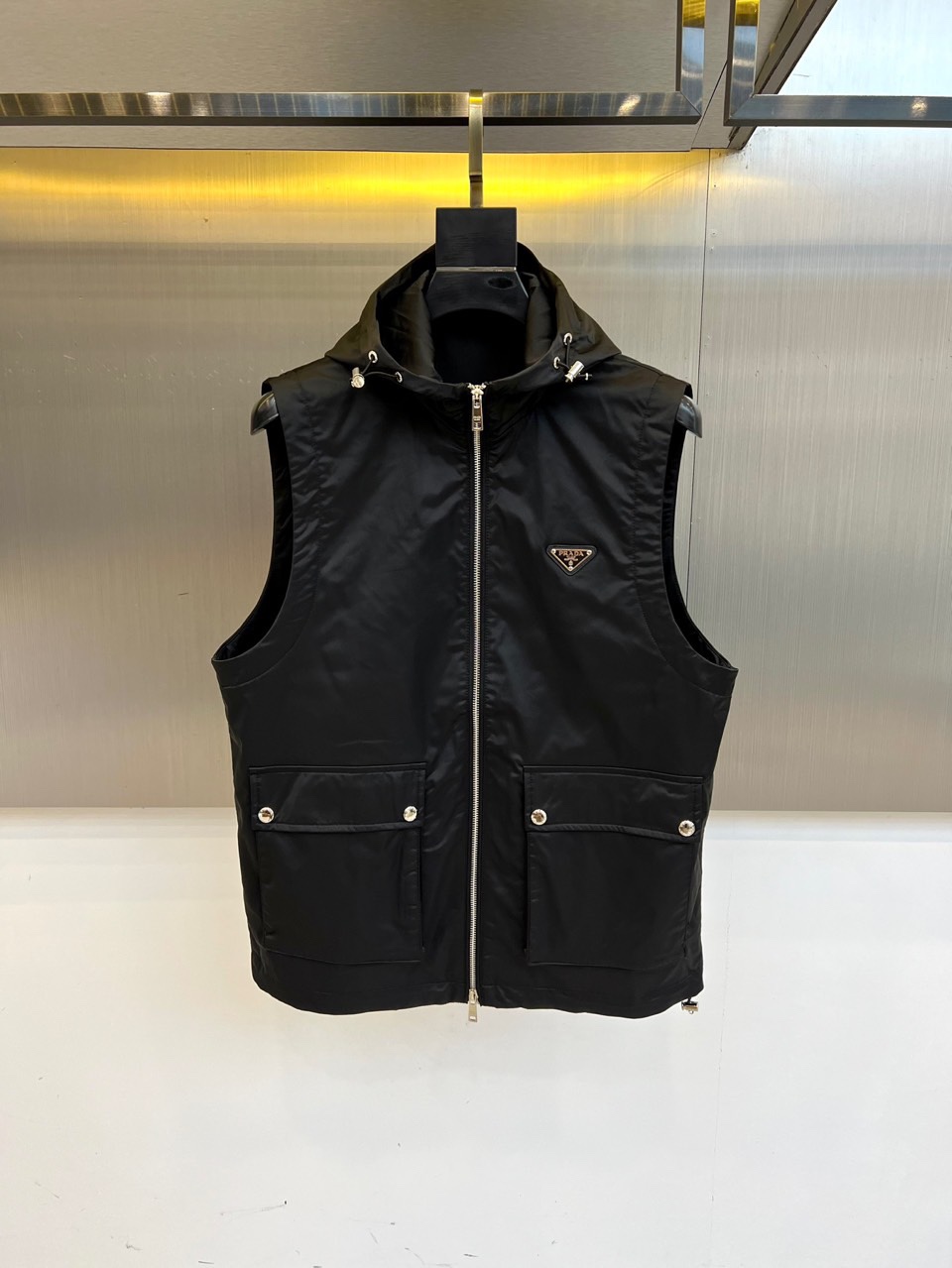 Prad普拉、25s秋冬新品男士连帽马甲。这款无袖连帽马甲以利落剪裁与机能美学打破常规——正面金属拉链开