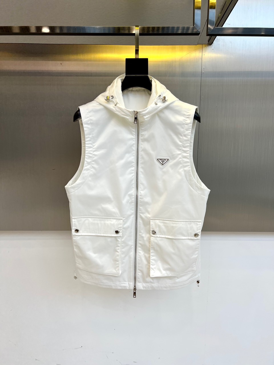 Prad普拉、25s秋冬新品男士连帽马甲。这款无袖连帽马甲以利落剪裁与机能美学打破常规——正面金属拉链开