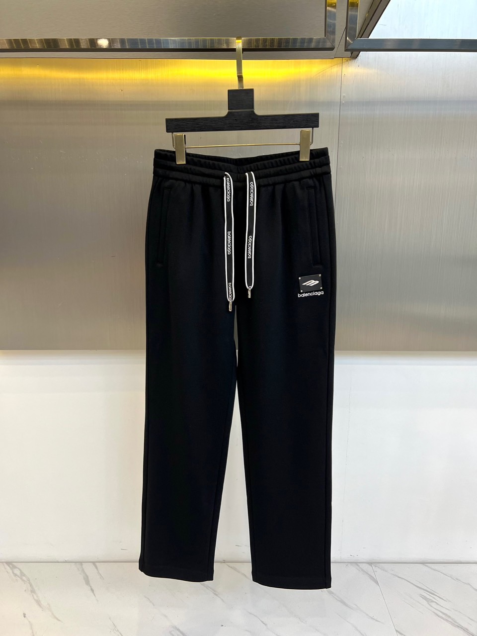 BALENCIAGA巴黎世家、2025秋冬新品男士束脚运动长裤，这款黑色长裤采用立体剪裁的束脚设计，腰部