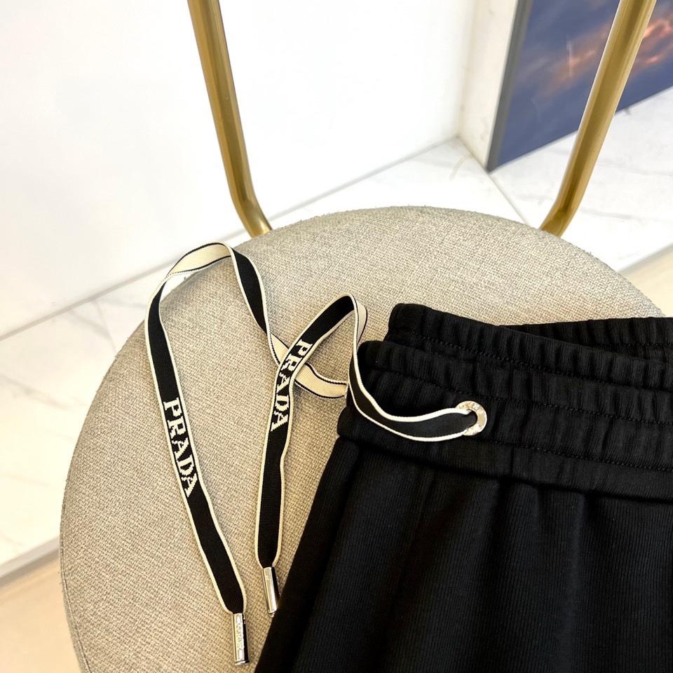 Prad普拉、2025秋冬新品风格男士休闲裤，这款黑色休闲裤采用PRADA标志性设计，左腿外侧饰有白色品