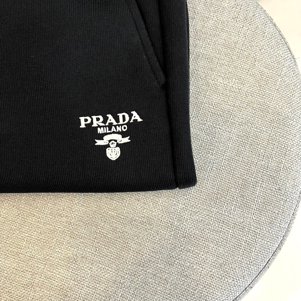 Prad普拉、2025秋冬新品风格男士休闲裤，这款黑色休闲裤采用PRADA标志性设计，左腿外侧饰有白色品