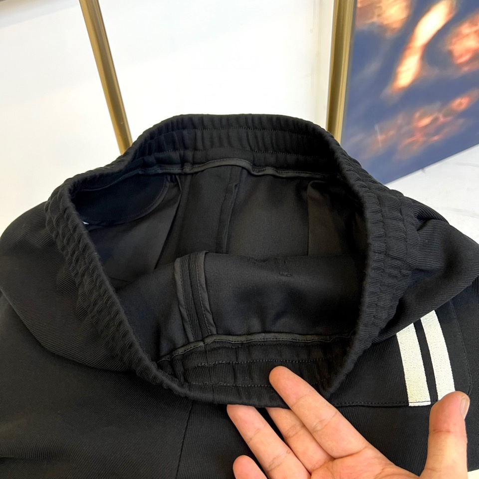 Prad普拉、2025秋冬新品风格男士休闲裤，这款黑色休闲裤采用PRADA标志性设计，左腿外侧饰有白色品