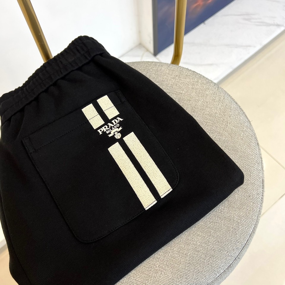 Prad普拉、2025秋冬新品风格男士休闲裤，这款黑色休闲裤采用PRADA标志性设计，左腿外侧饰有白色品