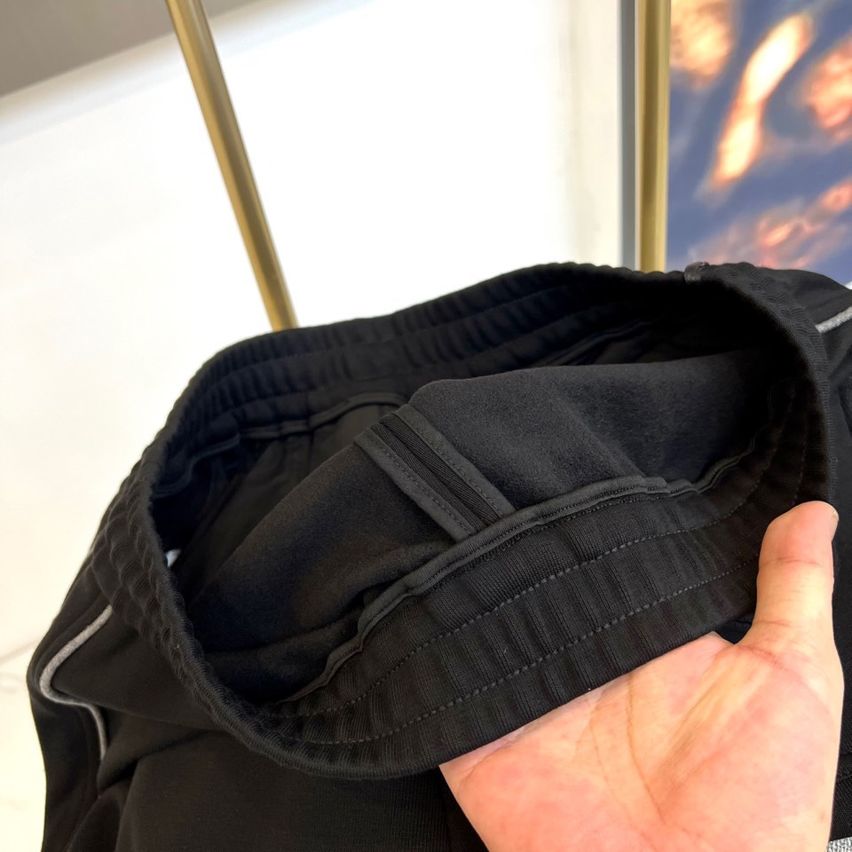 Mon蒙口、2025秋冬新品风格运动休闲裤。这款运动裤采用蒙口标志性设计，裤身两侧饰有浅灰色条纹，左侧裤