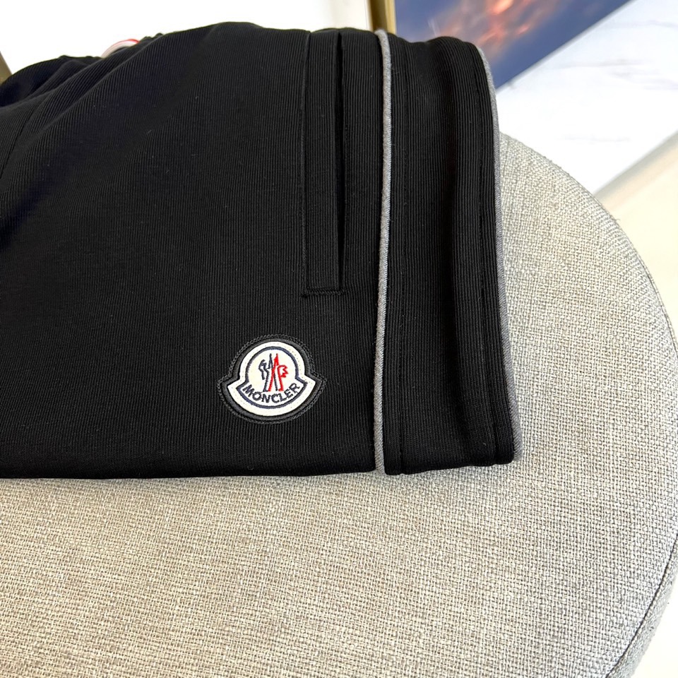 Mon蒙口、2025秋冬新品风格运动休闲裤。这款运动裤采用蒙口标志性设计，裤身两侧饰有浅灰色条纹，左侧裤