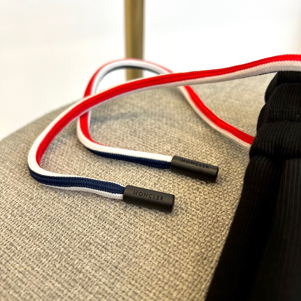 Mon蒙口、2025秋冬新品风格运动休闲裤。这款运动裤采用蒙口标志性设计，裤身两侧饰有浅灰色条纹，左侧裤