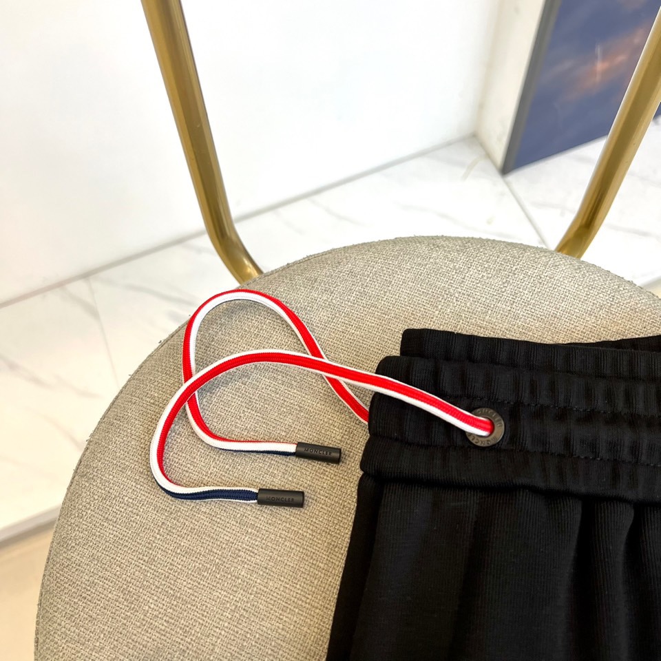 Mon蒙口、2025秋冬新品风格运动休闲裤。这款运动裤采用蒙口标志性设计，裤身两侧饰有浅灰色条纹，左侧裤