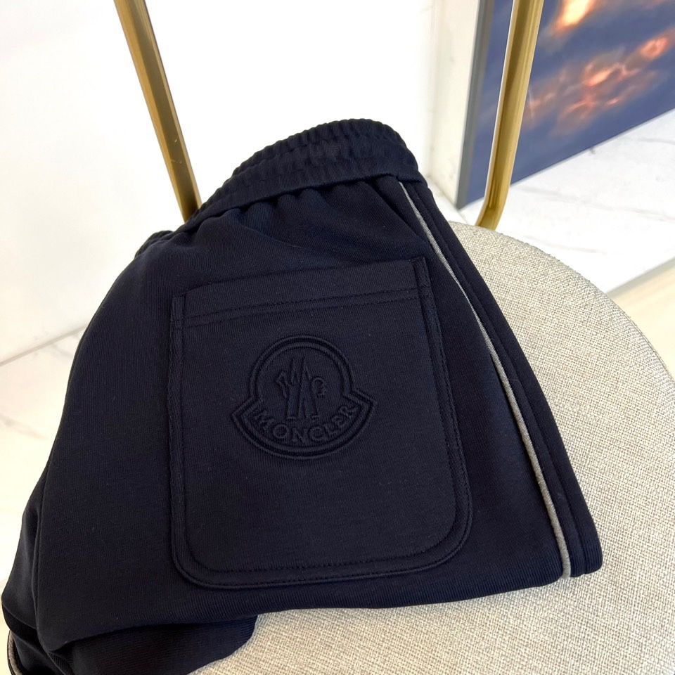 Mon蒙口、2025秋冬新品风格运动休闲裤。这款运动裤采用蒙口标志性设计，裤身两侧饰有浅灰色条纹，左侧裤