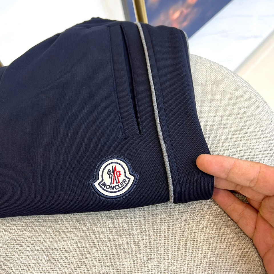 Mon蒙口、2025秋冬新品风格运动休闲裤。这款运动裤采用蒙口标志性设计，裤身两侧饰有浅灰色条纹，左侧裤