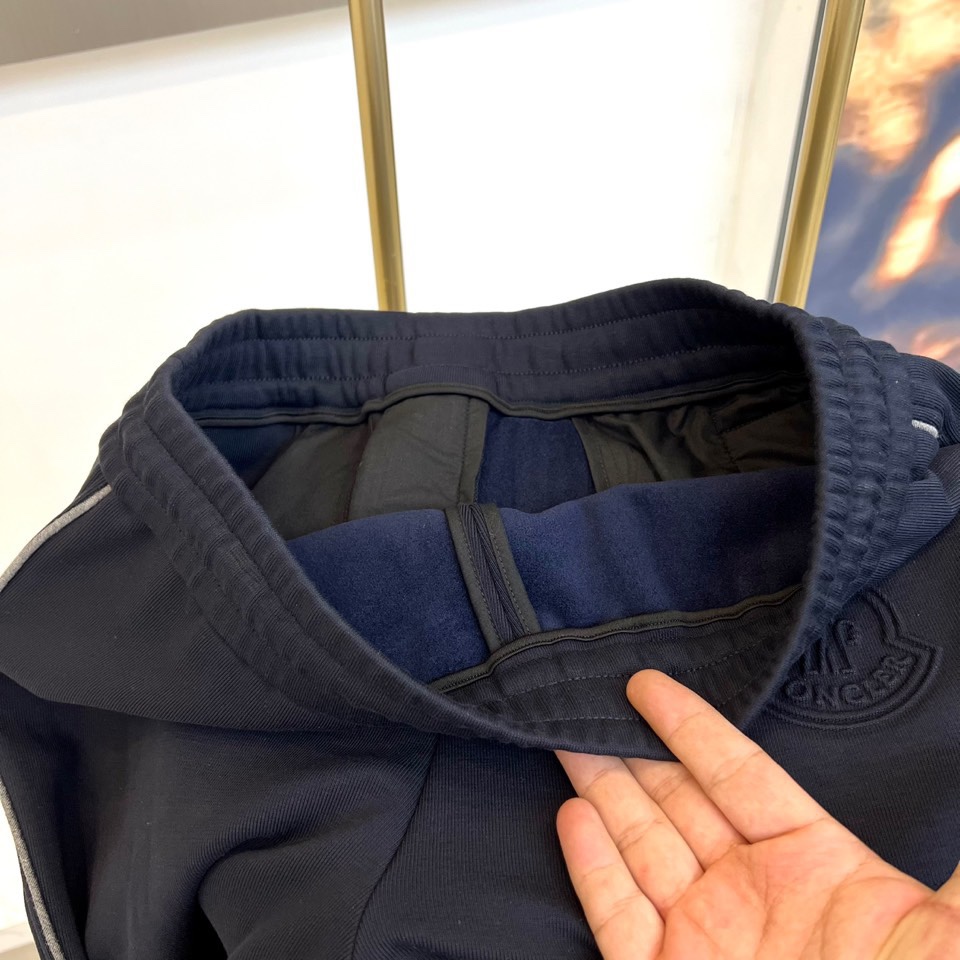 Mon蒙口、2025秋冬新品风格运动休闲裤。这款运动裤采用蒙口标志性设计，裤身两侧饰有浅灰色条纹，左侧裤