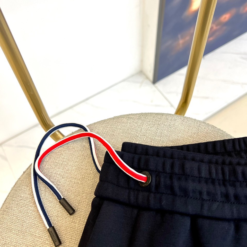 Mon蒙口、2025秋冬新品风格运动休闲裤。这款运动裤采用蒙口标志性设计，裤身两侧饰有浅灰色条纹，左侧裤