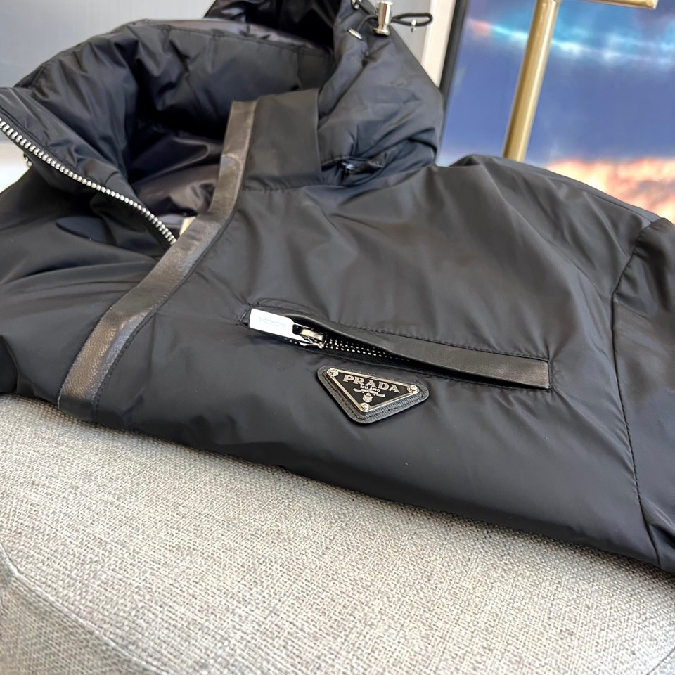 Prada普拉、2025秋冬新品羽绒服，以经典黑色演绎现代极简美学。这款羽绒服采用100%聚酰胺面料打造