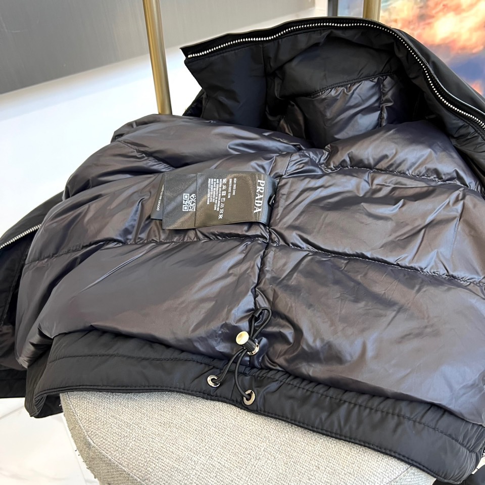 Prada普拉、2025秋冬新品羽绒服，以经典黑色演绎现代极简美学。这款羽绒服采用100%聚酰胺面料打造