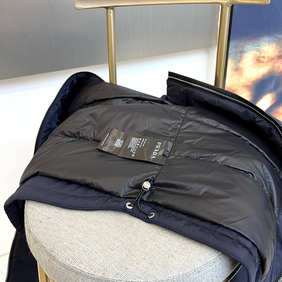 Prada普拉、2025秋冬新品羽绒服，以经典黑色演绎现代极简美学。这款羽绒服采用100%聚酰胺面料打造