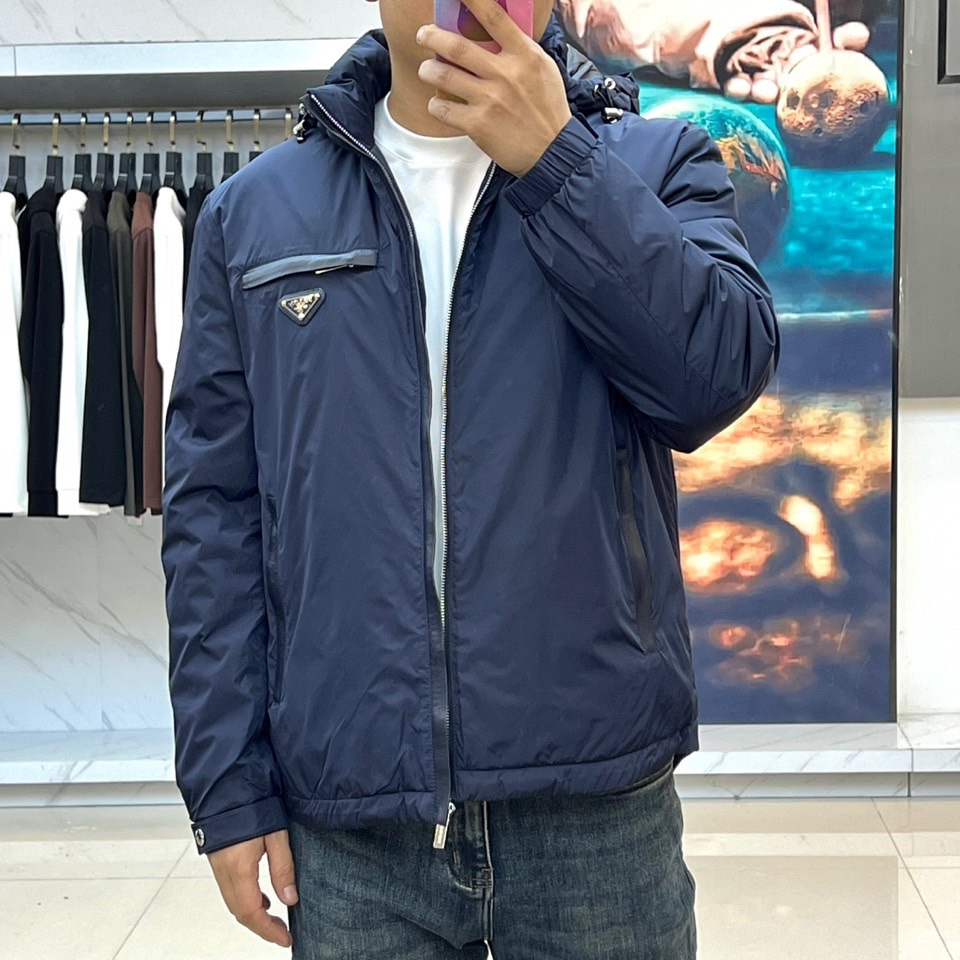 Prada普拉、2025秋冬新品羽绒服，以经典黑色演绎现代极简美学。这款羽绒服采用100%聚酰胺面料打造