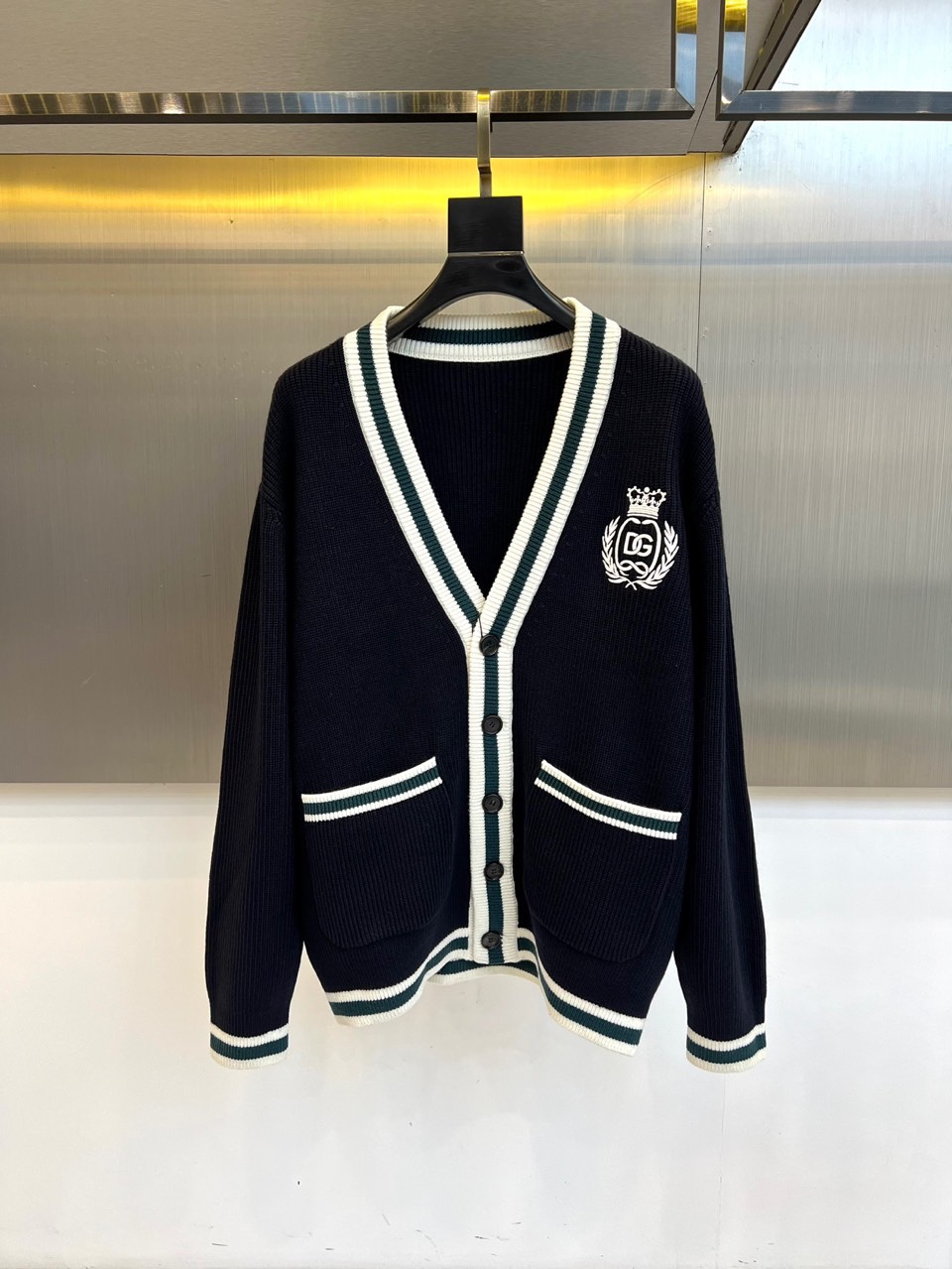 Dg杜嘉班纳、2025秋冬新品男士DG经典羊毛🐑针织开衫。这款藏青色开衫采用经典V领设计，领口、袖口及下