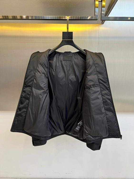Prad普拉、2025秋冬新品 PRADA科技防护羽绒服。深蓝色连帽设计搭配精密拉链系统，左胸红色织带镶