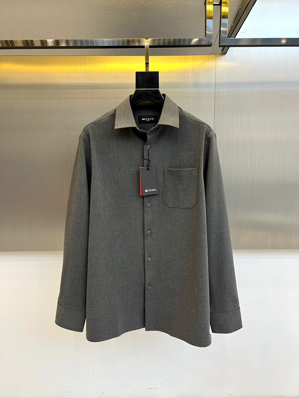 NO:726261,Kiton - a new autumn and winter craft shirt. This khaki shirt has a classic lapel design, five natural mother-of-pearl buttons on the front, and a flap pocket on the left chest. The edge of the pocket is outlined with red stitching to outline the delicate outline. The fabric is made of cotton, using traditional Italian textile techniques to present a fine twill texture. The collar and cuffs are padded to ensure a crisp and stylish look. The slim cut fits the figure of an elite man, and the khaki tone highlights a calm temperament.  The red stitching details inject a lively atmosphere into the simple design. It can be paired with a suit to create a business image or with casual pants to show an elegant daily style. It interprets KITON's aesthetic concept of integrating South Italian handicraft tradition with modern wearability. 48-56 (model 173, 143 pounds, upper body size 50), shirts, business suit,19860909年后 Kiton-秋冬新品匠心工艺衬衫.这款卡其色衬衫采用经典翻领设计,前襟搭配五颗天然母贝纽扣,左胸设有一个带盖口袋,袋边以红色缝线勾勒精致轮廓.面料选用棉质材质,通过意大利传统纺织工艺呈现细腻斜纹肌理,领口与袖口采用加衬工艺确保挺括有型.修身剪裁契合精英男士身形,卡其色基调彰显沉稳气质. 红色缝线细节为简约设计注入灵动气息,既可搭配西装塑造商务形象,也能配合休闲裤展现优雅日常风格.诠释KITON将南意手工传统与现代实穿性相融合的美学理念.48-56（模特173,143斤上身50码）,,shirts,business suit,,Men's clothing