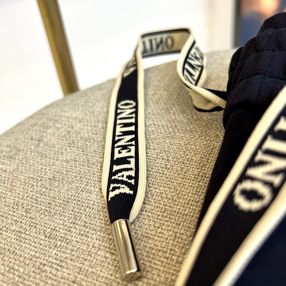 VT华伦天奴、2025秋冬新品风格休闲裤。这款束脚休闲裤采用华伦天奴标志性设计，裤腰配有黑色抽绳并印有白