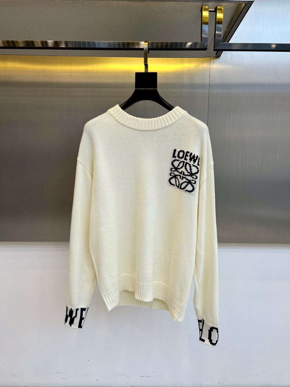 NO:597252,Lowe's new autumn and winter knitted sweaters use pure tones to interpret simple and luxurious modern aesthetics. This sweater is made of high-quality knitted fabrics, with a round neck design and a loose and moderate fit, creating a relaxed and moderate outline. The left chest is decorated with the brand's iconic monogram logo, which uses a three-dimensional weaving process to present a unique texture and highlight its extraordinary taste. The cuffs are embellished with black brand letter prints, adding details to the simple design. Exquisite knitting technology ensures that the fabric is soft and comfortable.  It is skin-friendly and has good elasticity. Whether it is paired with casual trousers to create a daily look, or combined with suit trousers to show a smart casual style, it can show the fashion attitude of a modern gentleman in a low-key and luxurious way. This sweater perfectly integrates Loewe's avant-garde design language and pragmatism, becoming an indispensable and versatile item in the autumn and winter wardrobe. 48-56 (model is 173,143 pounds, upper body size 50),,loewe,sweaters,business  suit,alexander wang19860909Lowe罗意威、秋冬新品针织毛衣,以纯净色调演绎简约奢华的现代美学.这款毛衣采用高品质针织面料,圆领设计搭配宽松适中的版型,营造出松弛有度的轮廓线条.左胸处装饰品牌标志性的字母交织标识,以立体编织工艺呈现独特质感,彰显不凡品味.袖口点缀黑色品牌字母印花,为简约设计增添细节亮点.精湛的针织工艺确保面料柔软亲肤且具有良好弹性,无论是搭配休闲长裤打造日常造型,还是与西装裤组合展现智能休闲风格,都能以低调奢华的方式展现现代绅士的时尚态度.这件毛衣将罗意威的前卫设计语言与实用主义完美融合,成为秋冬衣橱中不可或缺的百搭单品.48-56（模特173,143斤上身50码）,,loewe,sweaters,business suit,alexander wang,Men's clothing