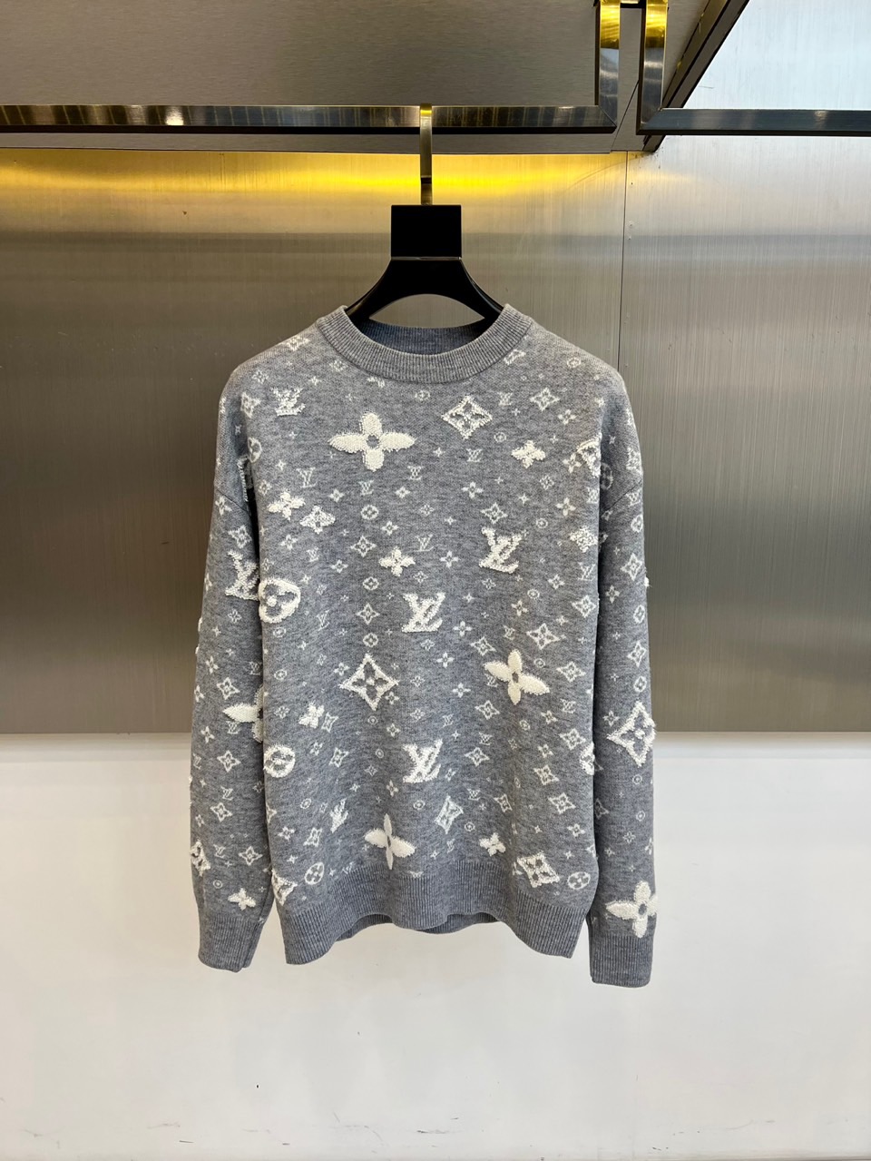 NO:597254,1v Vuitton's new autumn and winter knitted sweaters are based on high-end gray and reinterpret the brand's classic Monogram presbyopia pattern and four-leaf flower elements through three-dimensional jacquard technology. The round neck design is matched with a moderately loose fit to ensure wearing comfort while maintaining a neat silhouette. The surface of the sweater is covered with white presbyopia patterns of different sizes, and the patchwork arrangement forms a rhythmic visual hierarchy. Some patterns present an embossed touch through three-dimensional knitting technology. The cotton yarn has been specially processed  It is treated with spindle technology, which is both soft and skin-friendly and has good shape retention. The cuffs and hem adopt exquisite ribbing technology to enhance the durability of the clothing. This sweater transforms Louis Vuitton's classic genes into modern wearable art, whether it is paired with leather items  The product can show a modern style or be combined with casual trousers to create a low-key luxury style. It can become an iconic item that is both recognizable and practical in the autumn and winter wardrobe. 48-56 (model is 173, 143 pounds, upper body size 50),, louis  vuitton,sweaters,alexander wang198609091v威登、秋冬新品针织毛衣,以高级灰色为基调,将品牌经典Monogram老花图案与四叶花元素通过立体提花工艺重新演绎.圆领设计搭配适度宽松的版型,确保穿着舒适度的同时保持利落轮廓.毛衣表面布满大小不一的白色老花图案,错落有致的排列方式形成富有韵律感的视觉层次,部分图案通过立体针织技术呈现浮雕般的触感.棉质纱线经过特殊纺锤工艺处理,兼具柔软亲肤性与良好保形性.袖口与下摆采用精湛的罗纹收边工艺,增强服装的耐用性.这件毛衣将路易威登的经典基因转化为现代可穿戴艺术,无论是搭配皮革单品展现摩登型格,还是与休闲裤装组合营造低调奢华风范,都能成为秋冬衣橱中兼具辨识度与实穿度的标志性单品.48-56（模特173,143斤上身50码）,,louis vuitton,sweaters,alexander wang,Men's clothing