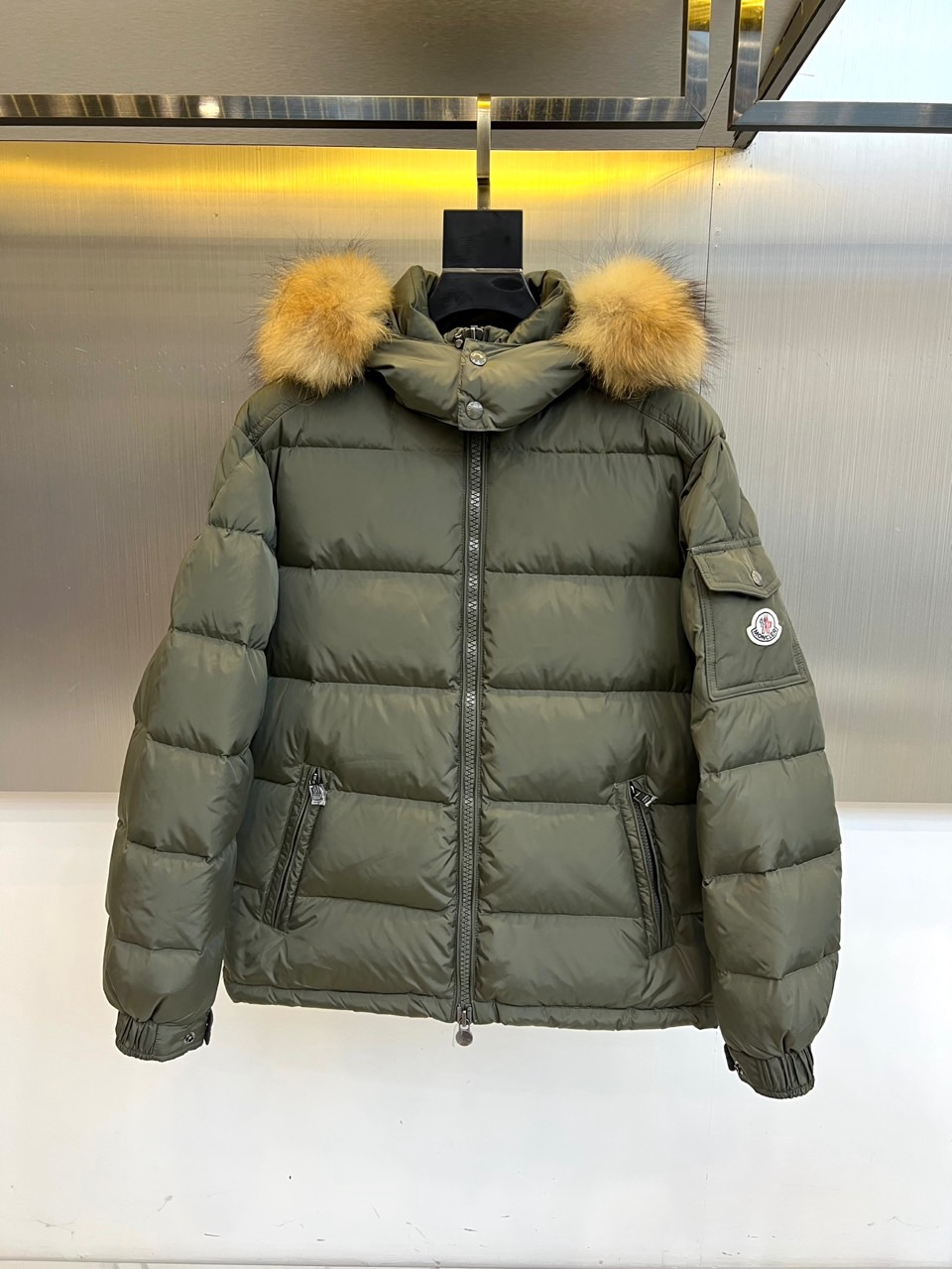 NO:596160,MON's new hooded down jacket for autumn and winter 2025 interprets urban outdoor aesthetics with a slim silhouette. The style adopts a hooded design with a detachable raccoon fur collar decoration. The side of the hood is decorated with fluffy light brown raccoon fur balls, which injects a smart atmosphere into the simple design. The front placket is equipped with a smooth black zipper  The chain closure system and diagonal pockets on both sides combine practical functions with smooth lines. The sleeves are decorated with the brand's iconic embroidered badges, and the body uses precise diamond quilting to ensure that 90% of high-quality down is evenly distributed. The fabric is made of high-performance windproof material, and the lining is marked with polyester fiber, made in Romania.  To ensure fine workmanship, the washing label recommends professional care to maintain fabric performance. Its three-dimensional tailoring optimizes the body proportions through a slim fit. It can be paired with bottoms of the same color to enhance the overall look, and can also be combined with casual items to create a mixed and matched level. From walking in the city to traveling in the suburbs, this down jacket features a raccoon coat.  The luxurious texture and professional down technology of the fur ball have become a winter model that connects alpine genes and daily fashion, interpreting MONCLER's continuous exploration of functional and aesthetic balance. Sizes 1-5 (model weighs 173,143 pounds, upper body size 2),,Moncler,down  jacket,hats,alexander wang19860909MON蒙口、2025秋冬新品连帽羽绒服,以修身廓形演绎都市户外美学.款式采用连帽设计搭配可拆卸貉子毛领装饰,帽侧点缀蓬松的浅棕色貉子毛球,为简约设计注入灵动气息.前襟配置顺滑黑色拉链开合系统,两侧斜插口袋兼顾实用功能与流畅线条.衣袖饰有品牌标志性刺绣徽章,衣身通过精准的菱形绗缝工艺确保90优质羽绒均匀分布.面料选用高性能防风材质,里料标注聚酯纤维,罗马尼亚制造确保精工品质,洗涤标签建议专业养护以保持面料性能.其立体剪裁通过修身版型优化身形比例,可搭配同色系下装强化整体感,亦能与休闲单品碰撞出混搭层次.从城市漫步到郊外出行,这款羽绒服以貉子毛球的奢华质感与专业羽绒工艺,成为连接高山基因与日常时尚的冬季典范,诠释MONCLER对功能与美学平衡的持续探索.1-5码（模特173,143斤上身2码）,,Moncler,down jacket,hats,alexander wang,Men's clothing