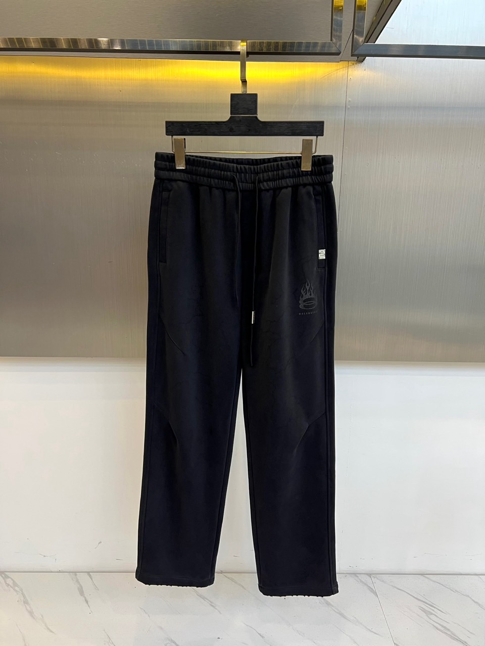 NO:599696,Balenciaga's new autumn and winter black casual trousers interpret contemporary street aesthetics with a loose straight silhouette. The style is designed with an elastic drawstring waistband, three-dimensional pockets on both sides are integrated with hidden stitching technology, and the left trouser leg is decorated with the brand's iconic logo print. The fabric is made of high-tech cotton blend material, which is specially processed to present a delicate texture, breathability and stiffness. Its design combines deconstruction and practicality, and can be matched with oversized  Sweatshirts enhance street style, and can also be combined with leather boots to create a mixed and matched level. From city walks to night socializing, these trousers, with the balance of iconic prints and three-dimensional tailoring, have become a carrier that connects high fashion genes and youth culture, interpreting Balenciaga's breakthrough exploration of traditional dressing rules. M-4XL (please state your height and weight when placing an order),,balenciaga,balenciaga,versace,boots,hoodie,sweatshirts,alexander wang19860909Balenciaga巴黎世家、秋冬新品黑色休闲长裤,以宽松直筒廓形诠释当代街头美学.款式采用弹性抽绳腰头设计,两侧立体插袋融入隐藏式缝线工艺,左裤腿饰有品牌标志性徽标印花.面料选用高科技棉质混纺材质,通过特殊处理呈现细腻肌理,兼具透气性与挺括度.其设计将解构主义与实穿性相融合,可搭配 oversized 卫衣强化街头风格,亦可与皮质靴款碰撞出混搭层次.从城市漫步到夜间社交,这款长裤以标志性印花与立体剪裁的平衡,成为连接高级时装基因与青年文化的载体,诠释Balenciaga对传统着装规则的突破性探索.M-4XL（下单请报身高体重）,,balenciaga,balenciaga,versace,boots,hoodie,sweatshirts,alexander wang,Men's clothing
