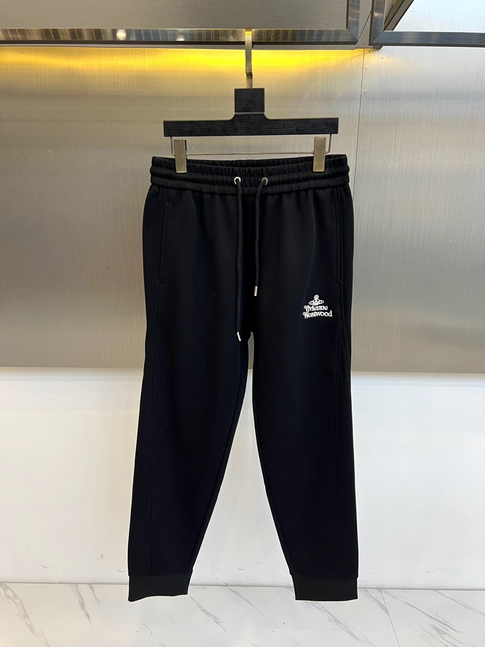 NO:599690,.Vivienne Westwood's new autumn and winter black casual sports pants continue the brand's rebellious spirit with its iconic design. The style adopts an elastic drawstring waist design, the trouser legs are slightly cuffed, and the left leg is decorated with white 'Vivienne'  Westwood' brand logo and classic Saturn pattern embroidery. The fabric is made of comfortable and elastic material to ensure freedom of daily activities. Its design combines punk genes with practical wearability. It can be paired with a leather jacket to enhance the rock style, or it can be combined with a simple top for a fun mix and match. From  From walking on the streets to music scenes, these trousers balance the rebellious genes of the Saturn totem with the sporty silhouette, becoming a carrier that connects the brand spirit and daily wear, interpreting the Queen Mother's eternal pursuit of free expression. M-4XL (please state your height and weight when placing an order),,jackets  & coats,alexander wang19860909.Vivienne Westwood 西太后、秋冬新品黑色休闲运动裤,以标志性设计延续品牌叛逆精神.款式采用弹性抽绳腰头设计,裤腿微束口剪裁,左腿处饰有白色'Vivienne Westwood'品牌标识与经典土星图案刺绣.面料选用舒适弹性材质,确保日常活动自由度.其设计将朋克基因与实穿性相融合,可搭配皮革外套强化摇滚风格,亦可与简约上衣碰撞出混搭趣味.从街头漫步到音乐现场,这款长裤以土星图腾的叛逆基因与运动廓形的平衡,成为连接品牌精神与日常着装的载体,诠释西太后对自由表达的永恒追求.M-4XL（下单请报身高体重）,,jackets & coats,alexander wang,Men's clothing