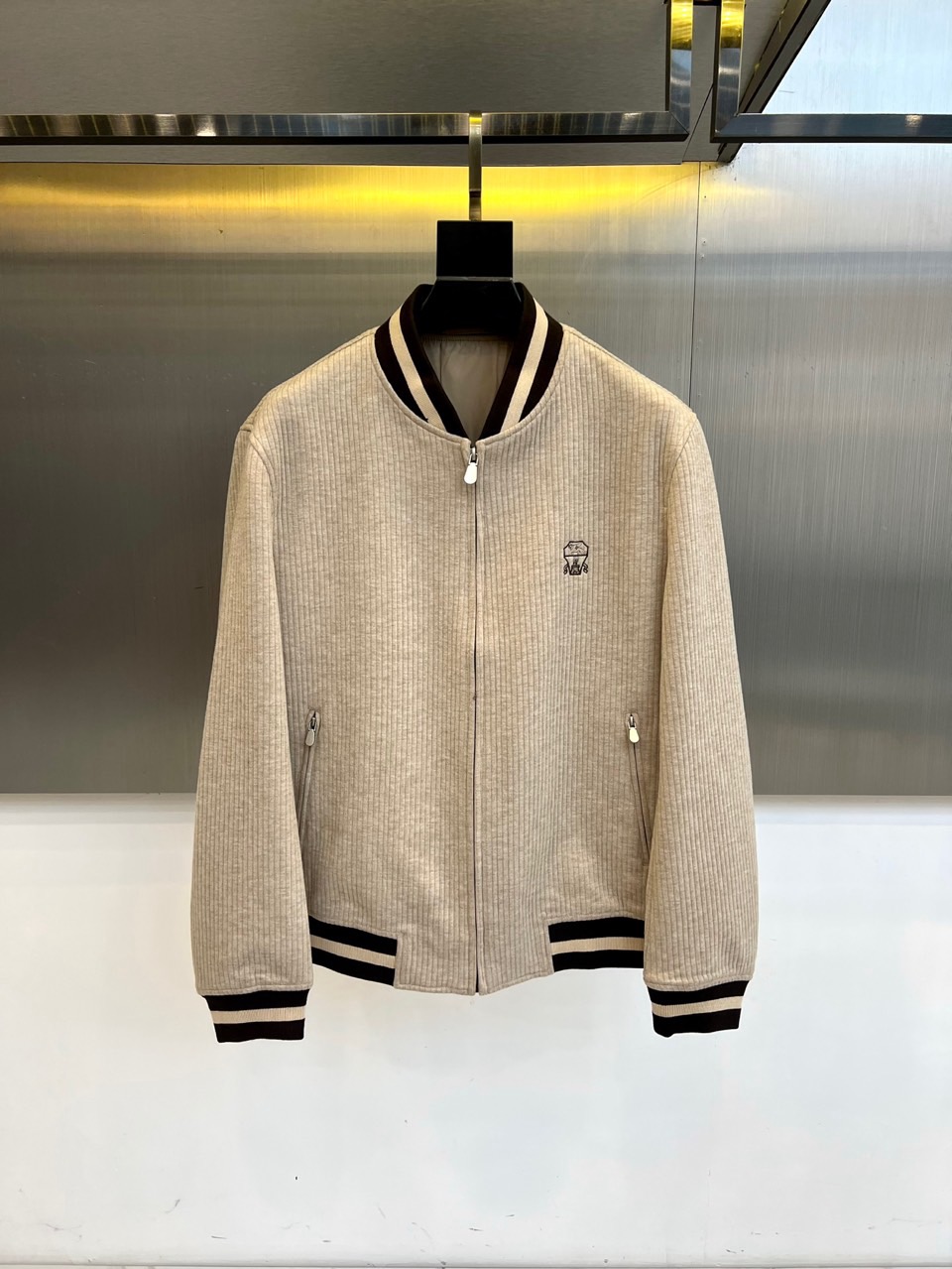 NO:597475,Brunello Cucinelli  The new jacket for autumn and winter 2025 uses light gray vertical striped fabric to interpret urban functional aesthetics. The style adopts a stand-up collar design with a smooth silver zipper. The collar, cuffs and hem are decorated with black and white stripes to form a distinct visual hierarchy. Both sides of the body are equipped with practical zippered openings.  The bag is embellished with the brand's exquisite embroidered badge on the left chest. The fabric is made of innovative blended materials, including 38 rayon to provide skin-friendly breathability, 18 nylon to enhance wear resistance, 40 polyester to ensure a crisp silhouette, and 4 spandex to provide elasticity; the lining is made of polyester fiber to ensure wearing comfort.  Its three-dimensional tailoring optimizes the body line through vertical stripe texture. It can be paired with casual trousers to create a business casual style, or it can be combined with items from the same series to create an overall sense of style. From business meetings to city exploration, this jacket is designed with humanized fabric proportions and sporty details to become a carrier that connects Italian craftsmanship and modern life, interpreting the brand's contemporary interpretation of low-key luxury. It is recommended to hand wash gently to maintain the texture of the fabric. 48-56 (model 173, 143 pounds, upper body size 50), brunello  cucinelli,jackets & coats,alexander wang19860909Brunello Cucinelli 2025秋冬新品夹克,以浅灰色竖条纹面料演绎都市机能美学.款式采用立领设计搭配顺滑银色拉链,领口、袖口及下摆处饰以黑白相间条纹,形成鲜明视觉层次.衣身两侧配备带拉链的实用口袋,左胸点缀品牌精致刺绣徽章.面料选用创新混纺材质,含38人棉赋予亲肤透气性,18锦纶增强耐磨度,40涤纶保证廓形挺括,4氨纶提供活动弹性；内里采用聚酯纤维,确保穿着舒适度. 其立体剪裁通过竖条纹纹理优化身形线条,可搭配休闲长裤打造商务休闲风范,亦可与同系列单品碰撞出整体造型感.从商务会晤到城市探索,这款夹克以人性化的面料配比与运动感细节设计,成为连接意式工艺与现代生活的载体,诠释品牌对低调奢华的当代解读.建议轻柔手洗维护面料质感.48-56（模特173,143斤上身50码）,,brunello cucinelli,jackets & coats,alexander wang,Men's clothing