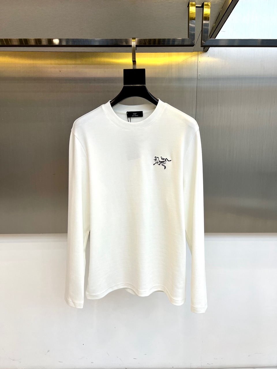 NO:597458,ARC'TERYX  Arc'teryx, the new long-sleeved T-shirt for autumn and winter 2025, interprets outdoor functional aesthetics with a minimalist design. The style adopts a classic round neck cut, and the left chest is embellished with the brand's iconic black embroidered 'ARC'TERYX' letter logo, with fine and neat stitching.  It shows exquisite craftsmanship. The fabric is made of high-quality cotton, which is specially processed to present a delicate texture and ensure skin-friendly breathability. The pattern is three-dimensional and has space for movement reserved at the shoulder line and armholes, which not only maintains the slimming effect but also allows for freedom of movement.  Its design integrates mountain genes into daily wear. It can be worn alone with hiking pants to enhance outdoor style, or layered with casual jackets. From urban commuting to suburban exploration, this T-shirt balances iconic embroidery and practical styles to become a carrier that connects outdoor functions and urban life. The label indicates professional washing and maintenance methods, explaining Arc'teryx's persistent pursuit of quality details. 48-56 (model 173, 143 pounds, upper body size 50), arc'teryx, jackets &  coats,tees,t-shirt,alexander wang19860909ARC'TERYX 始祖鸟、2025秋冬新品长袖T恤,以极简设计诠释户外机能美学.款式采用经典圆领剪裁,左胸点缀品牌标志性黑色刺绣'ARC'TERYX'字母标识,缝线细密工整彰显精湛工艺.面料选用高品质棉质材质,通过特殊处理呈现细腻肌理感,确保亲肤透气性.版型采用立体剪裁,在肩线与袖笼处预留活动空间,既保持修身效果又兼顾运动自由度. 其设计将山地基因融入日常着装,可单独搭配徒步裤强化户外风格,亦可与休闲外套层叠穿搭.从城市通勤到近郊探索,这款T恤以标志性刺绣与实用版型的平衡,成为连接户外功能与都市生活的载体.标签注明专业洗涤养护方式,诠释始祖鸟对品质细节的执着追求.48-56（模特173,143斤上身50码）,arc'teryx,jackets & coats,tees，t-shirt,alexander wang,Men's clothing