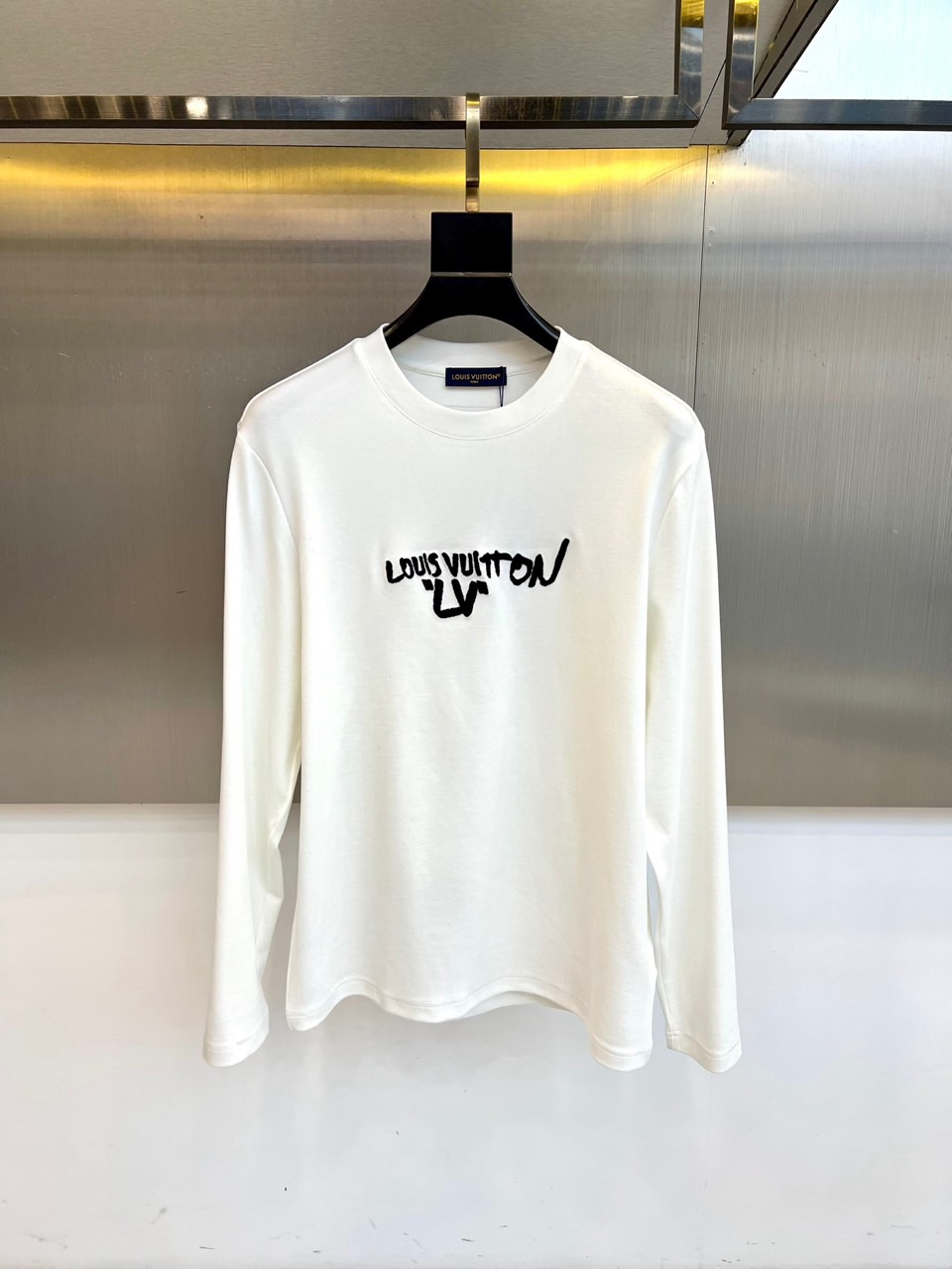 NO:597461,LOUIS VUITTON's 2025 autumn and winter new long-sleeved T-shirt interprets modern luxury aesthetics with minimalist design. The style adopts a classic round neck design, and the body is made of high-quality cotton fabric to ensure skin-friendly and breathable. The biggest highlight is the black artistic graffiti design on the chest - the brand logo 'LOUIS' is outlined with splashed ink strokes  VUITTON' words, and blended with the classic LV presbyopia pattern, forming a collision between street art and luxury genes. The graffiti part is treated with a special printing process to ensure that the pattern is long-lasting and clear.  Its design combines high fashion genes with street culture. It can be worn alone with jeans to show casual fashion, or as an inner layer with a suit jacket. From daily outings to high-end social occasions, this T-shirt has the visual tension of artistic graffiti and precise tailoring technology, becoming a fashion carrier that connects the brand's century-old heritage and youth culture. It is recommended to follow the label guidance for professional maintenance to maintain the fabric texture and pattern brightness. 48-56 (model 173, 143 pounds, upper body size 50), Louis  vuitton,louis vuitton,jeans,jackets & coats,tees,t-shirt,business suit,alexander wang19860909LOUIS VUITTON 2025秋冬新品长袖T恤,以极简主义设计诠释现代奢华美学.款式采用经典圆领设计,衣身选用高品质棉质面料确保亲肤透气性.最大亮点在于胸前的黑色艺术涂鸦设计——以泼墨笔触勾勒品牌标识'LOUIS VUITTON'字样,并与经典LV老花图案交融,形成街头艺术与奢侈基因的碰撞.涂鸦部分采用特殊印花工艺处理,确保图案持久清晰. 其设计将高级时装基因与街头文化相融合,可单独搭配牛仔裤展现休闲时尚,亦可作为内搭与西装外套层叠穿搭.从日常出街到高端社交场合,这款T恤以艺术涂鸦的视觉张力与精准剪裁工艺,成为连接品牌百年传承与青年文化的时尚载体.建议遵循标签指导进行专业养护,保持面料质感与图案鲜艳度.48-56（模特173,143斤上身50码）,,louis vuitton,louis vuitton,jeans,jackets & coats,tees，t-shirt,business suit,alexander wang,Men's clothing