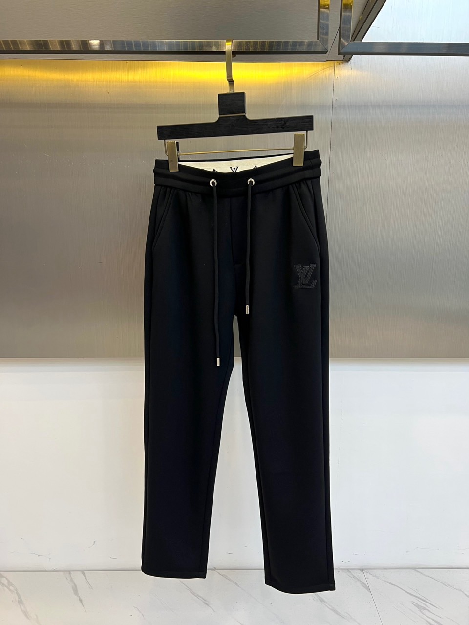 NO:597476,1v Vuitton, 2025 autumn and winter new black casual trousers, interprets modern urban aesthetics with a classic straight silhouette. The style adopts an elastic drawstring waist design with convenient adjustment functions. The right side of the trousers is embellished with the brand's iconic letter embroidery badge. The fabric is made of high-tech elastic material and is treated with a special process to present a delicate texture to ensure freedom of movement and comfortable experience when wearing. Its design will focus on practicality  The meaning is integrated with the brand's genes. It can be paired with a white sweater to create a simple look, or it can be combined with a leather jacket to create a mixed style. From daily commuting to casual socializing, these trousers, with iconic details and three-dimensional cutting technology, have become a fashion carrier that connects brand heritage and contemporary life, interpreting Louis Vuitton's in-depth exploration of daily dress aesthetics. M-4XL (please state your height and weight when placing an order),, louis  vuitton,jackets & coats,alexander wang198609091v威登、2025秋冬新品黑色休闲长裤,以经典直筒廓形诠释现代都市美学.款式采用弹性抽绳腰头设计,搭配便捷的调节功能,右侧裤身点缀品牌标志性字母刺绣徽章.面料选用高科技弹性材质,通过特殊工艺处理呈现细腻肌理感,确保穿着时的活动自由度与舒适体验.其设计将实用主义与品牌基因相融合,可搭配白色针织衫打造简约造型,亦可与皮革外套碰撞出混搭风格.从日常通勤到休闲社交,这款长裤以标志性细节与立体剪裁工艺,成为连接品牌传承与当代生活的时尚载体,诠释路易威登对日常着装美学的深度探索.M-4XL（下单请报身高体重）,,louis vuitton,jackets & coats,alexander wang,Men's clothing