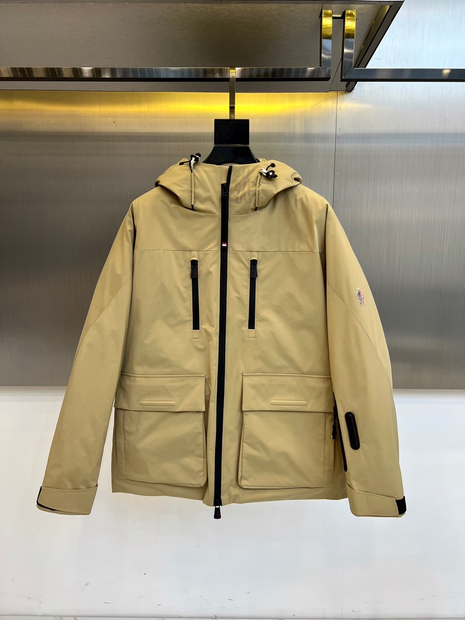 NO:597485,Mon (goose down), 2025 autumn and winter new ski clothing, uses khaki tones to interpret professional ski resort aesthetics. The style adopts a hooded design with an adjustable black drawstring, the placket is equipped with a windproof zipper system, and four zippered multi-functional pockets are symmetrically set on both sides.  Taking care of storage safety and visual balance. The left sleeve is embellished with the brand's iconic badge, and the body is three-dimensionally cut to reserve space for movement and stretching. The fabric is made of high-performance windproof material, and the filling strictly follows the American down and feather product label standards, including 90% goose down and 10% feather.  The golden ratio ensures warmth in extremely cold environments. Its design combines Alpine skiing genes with practical functions. It can be paired with professional snow pants to complete the equipment system, and can also be integrated into daily urban wear. From alpine ski trails to winter journeys, this ski suit features rigorous craftsmanship.  Standards and humanized details have become winter equipment that connects professional protection and fashion attitude, interpreting Moncler's in-depth exploration of ice and snow sports aesthetics. 48-56 (model weighs 173,143 pounds, upper body size 50),,Moncler,down  jacket,gold,hats,alexander wang19860909Mon蒙口（鹅绒）、2025秋冬新品滑雪服,以卡其色基调演绎专业雪场美学.款式采用连帽设计搭配可调节黑色抽绳,门襟配置防风拉链系统,两侧对称设置四个带拉链的多功能口袋,兼顾储物安全性与视觉平衡感.左袖点缀品牌标志性徽章,衣身通过立体剪裁预留运动伸展空间.面料采用高性能防风材质,填充物严格遵循美国年羽绒羽毛制品标签标准,含90鹅绒与10羽毛的黄金配比,确保极寒环境下的保暖效能.其设计将阿尔卑斯滑雪基因与实用功能相融合,可搭配专业雪裤完善装备体系,亦能融入都市日常穿搭.从高山雪道到冬季旅途,这款滑雪服以严谨的工艺标准与人性化细节,成为连接专业防护与时尚态度的冬季装备,诠释Moncler对冰雪运动美学的深度探索.48-56（模特173,143斤上身50码）,,Moncler,down jacket,gold,hats,alexander wang,Men's clothing