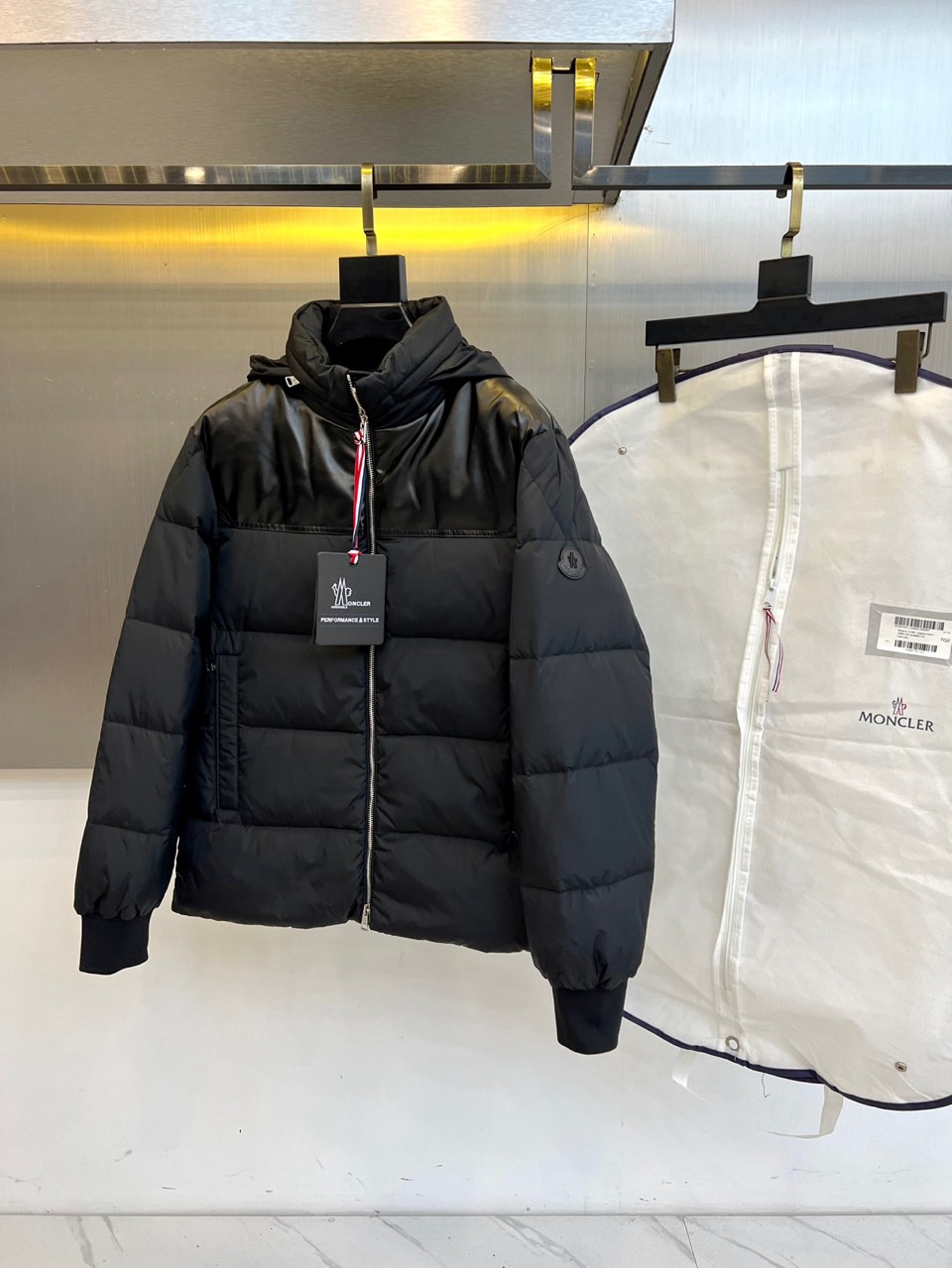 NO:597459,Mon (goose down + sheepskin), 2025 autumn and winter new black down jacket (with dust bag), uses innovative materials to collide to interpret urban functional aesthetics. The style adopts a hooded design, the upper part is made of textured leather material, and the lower part is filled with 90 high-quality white goose through diamond quilting technology  Velvet creates a unique visual segmentation effect. The front is equipped with a smooth silver zipper, and the left sleeve is embellished with the brand's classic circular badge. A detailed material label is hung on the collar, clearly indicating that the fabric and lining are made of nylon. The filling content is 90% white goose down, and it is made in Romania to ensure precision workmanship.  Its design combines the tough texture of sheepskin with the soft and fluffy feel of down. It can be paired with trousers of the same color to enhance the overall look, and can also be combined with casual items to create a mix and match. From urban street scenes to winter travel, this down jacket combines the ingenuity and professionalism of contrasting materials.  With its professional thermal insulation performance, it has become a carrier that connects outdoor genes and fashion attitudes, interpreting Moncler's continuous exploration of technological innovation and practical aesthetics. Sizes 1-5 (model weighs 173,143 pounds, upper body size 2),,Moncler,down  jacket,sheepskin,hats,alexander wang19860909Mon蒙口（鹅绒+绵羊皮）、2025秋冬新品黑色羽绒服（配防尘袋）,以创新材质碰撞诠释都市机能美学.款式采用连帽设计,上半部分选用质感皮革材质,下半部分通过菱形绗缝工艺填充90高品质白鹅绒绒,形成独特的视觉分割效果.前襟配置顺滑银色拉链,左袖点缀品牌经典圆形徽章,领口悬挂详细材质标签,明确标注面料与里料均采用锦纶材质,填充物含绒量达90白鹅绒,罗马尼亚制造确保精工品质. 其设计将绵羊皮的硬朗质感与羽绒的柔软蓬松相融合,可搭配同色系裤装强化整体造型感,亦能与休闲单品碰撞出混搭层次.从都市街景到冬季出行,这款羽绒服以材质对比的巧思与专业保暖性能,成为连接户外基因与时尚态度的载体,诠释Moncler对工艺创新与实用美学的持续探索.1-5码（模特173,143斤上身2码）,,Moncler,down jacket,sheepskin,hats,alexander wang,Men's clothing