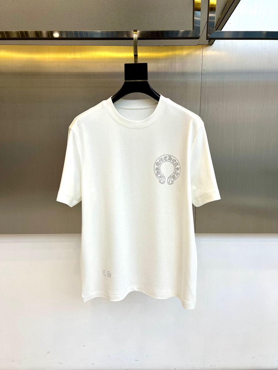 NO:597465,Chrome Hearts  Crow Heart, the new short-sleeved T-shirt for autumn and winter 2025, interprets dark luxury aesthetics with a minimalist silhouette. The style adopts a classic round neck design, and the left chest is embellished with the brand's iconic horseshoe and crown combination badge. The badge uses distressed silver craftsmanship to present a three-dimensional texture, and the hem is exquisitely embroidered.  'CH' letter logo. The fabric is made of a precise ratio of 47 modal, 47 cotton and 6 spandex, which not only maintains the silky drape of modal, but also ensures breathability through cotton, and the spandex component provides moderate elasticity. Its design injects Gothic silverware aesthetics into daily wear, which can  Pair it with leather items to enhance the rock and roll style, or it can be combined with denim materials to create a mixed and matched level. From walking on the street to socializing at night, this T-shirt uses hand-made badge details and exquisite fabric matching to become a carrier that connects silverware art and daily wear, interpreting Crowe's love for darkness.  An in-depth exploration of aesthetics. The washing label clearly guides professional maintenance methods such as hand washing at 30°C low temperature, no bleaching, hanging to dry, etc. to ensure that the silver badge maintains its timeless texture. 48-56 (model is 173,143 pounds, upper body size 50),, chrome  hearts,chrome hearts,T-shirt,tees,t-shirt,alexander wang19860909Chrome Hearts 克罗心、2025秋冬新品短袖T恤,以极简轮廓诠释暗黑奢华美学.款式采用经典圆领设计,左胸点缀品牌标志性马蹄铁与皇冠组合徽章,徽章采用做旧银饰工艺呈现立体质感,下摆处绣有精致的'CH'字母标识.面料选用47莫代尔、47棉与6氨纶的精密配比,既保持莫代尔的丝滑垂坠感,又通过棉质确保透气性,氨纶成分提供适度弹性.其设计将哥特式银饰美学注入日常着装,可搭配皮革单品强化摇滚气质,亦可与牛仔材质碰撞出混搭层次.从街头漫步到夜间社交,这款T恤以手工级的徽章细节与考究的面料配比,成为连接银器艺术与日常穿着的载体,诠释克罗心对暗黑美学的深度探索.洗涤标签明确指导30℃低温手洗、不可漂白、悬挂晾干等专业养护方式,确保银饰徽章保持历久弥新的质感.48-56（模特173,143斤上身50码）,,chrome hearts,chrome hearts,T-shirt,tees，t-shirt,alexander wang,Men's clothing