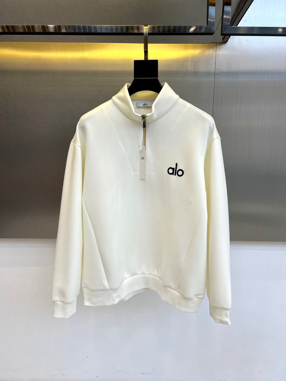 NO:598618,ALO-2025 autumn and winter new product ALO air layer half-zip sweatshirt. Made of air layer fabric with a scientific ratio of 47 modal + 53 cotton. Modal fiber gives a double-sided brushed texture with a cloud-like soft and waxy touch. The cotton base ensures breathability and skin-friendlyness. The half-zip stand-up collar design can freely adjust the breathability with body temperature. The brand's iconic black 'alo' logo is embroidered on the left chest. The cuffs and hem adopt high-elastic ribbing technology.  Three-dimensional tailoring enables zero-restraint movement, and the air layer structure forms a thermal insulation layer. The white tone is suitable for yoga training and urban life scenes. It can be paired with sports pants to create a casual look, or a windproof jacket to create a layered look. Through the combination of material innovation and practical design, it interprets ALO's brand philosophy of integrating sports technology into daily wear. 48-56 (model 173,143 pounds, upper body size 50),,hoodie,sweatshirts,jackets & coats,alexander wang19860909ALO-2025秋冬新品ALO空气层半拉链卫衣. 采用47莫代尔+53棉科学配比的空气层面料,莫代尔纤维赋予双面磨毛肌理云朵般柔糯触感,棉质基底保证透气亲肤性.半拉链立领设计可随体温自由调节透气度,左胸刺绣品牌标志性黑色'alo'标识,袖口与下摆采用高弹罗纹收边工艺. 立体剪裁实现运动零束缚,空气层结构形成保温隔热层.白色基调适配瑜伽训练与都市生活场景,可搭配运动裤打造休闲造型,或外搭防风外套构建层次穿搭.通过材质创新与实用设计的结合,诠释ALO将运动科技融入日常穿着的品牌哲学.48-56（模特173,143斤上身50码）,,hoodie,sweatshirts,jackets & coats,alexander wang,Men's clothing