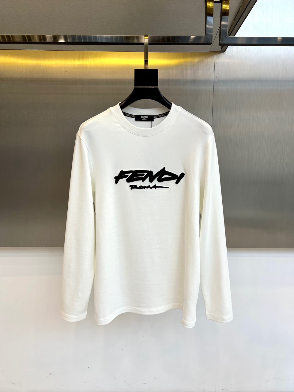 NO:598626,Fendi, 2025 autumn and winter new long-sleeved T-shirt, interprets French luxury aesthetics with minimalist design. The style adopts a classic round neck design, and the body is made of high-quality cotton material to ensure skin-friendly breathability. The brand's iconic black 'FENDI' handwritten style logo is embellished on the chest, which contrasts sharply with the white base, highlighting a sense of low-key luxury. Its design combines the brand's century-old heritage with modern practicality, and can be paired with jeans  trousers to create a casual look, or can be combined with trousers to create a light business style. From daily outings to high-end social occasions, this T-shirt, with its simple logo design and precise tailoring technology, has become a fashion carrier that connects travel genes and urban life, interpreting LV's eternal pursuit of classics and innovation. 48-56 (model 173, 143 pounds, upper body size 50),, fendi, fendi, louis  vuitton,jeans,tees,t-shirt,alexander wang19860909芬迪、2025秋冬新品长袖T恤,以极简设计诠释法式奢华美学.款式采用经典圆领设计,衣身选用高品质棉质材质确保亲肤透气性,胸前点缀品牌标志性黑色'FENDI'手写风格标识,与白色基底形成鲜明对比,彰显低调奢华感.其设计将品牌百年传承与现代实穿性相融合,可搭配牛仔裤打造休闲造型,亦可与西裤碰撞出轻商务风格.从日常出街到高端社交场合,这款T恤以简约的标识设计与精准剪裁工艺,成为连接旅行基因与都市生活的时尚载体,诠释LV对经典与创新的永恒追求.48-56（模特173,143斤上身50码）,,fendi,fendi,louis vuitton,jeans,tees，t-shirt,alexander wang,Men's clothing