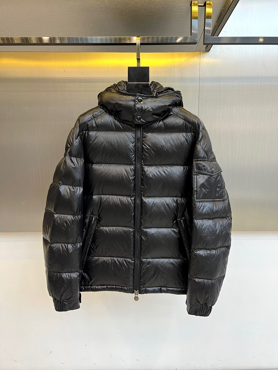 NO:598625,Moncler's new men's down jacket for autumn and winter 2025 (high-end duck down version) uses classic black to interpret urban functional aesthetics. The style adopts a hooded design, and the front panel is made of bright windproof fabric and formed into three-dimensional divisions through horizontal quilting technology. There are practical slip pockets on both sides of the body, and the left sleeve is equipped with a zipper pocket to enhance the storage function. The fabric and lining are made of nylon, filled with high-quality white duck down with 90% down content, and strictly comply with the GB/T14272-down standard.  Its design combines professional protective genes with modern tailoring. Horizontal quilting ensures even distribution of down, and glossy material enhances the visual texture. It can be paired with casual trousers to create an urban look, and can also meet the needs of outdoor activities. From commuting in the city to traveling in the suburbs, this down jacket has a high charge of 309 grams.  The excellent warmth brought by the down volume, practical pocket details and neat silhouette have become a winter item that connects functionality and fashion, explaining the brand's dual pursuit of quality and aesthetics. 48-56 (model weighs 173,143 pounds, upper body size 50),,Moncler,down  jacket,hats,alexander wang19860909Moncler蒙口（鸭绒版本高端玛雅）、2025秋冬新品男士羽绒服,以经典黑色演绎都市机能美学.款式采用连帽设计,前片选用亮面防风面料并通过横向绗缝工艺形成立体分割,衣身两侧设实用插袋,左袖配置拉链口袋增强储物功能.面料与里料均采用锦纶材质,填充90绒子含量的优质白鸭绒,严格执行GB/T14272-羽绒标准. 其设计将专业防护基因与现代剪裁相融合,横向绗缝确保羽绒均匀分布,亮面材质提升视觉质感.可搭配休闲长裤打造都市造型,亦能满足户外活动需求.从城市通勤到郊外出行,这款羽绒服以309克高充绒量带来的卓越保暖性、实用口袋细节与利落版型,成为连接功能性与时尚感的冬季单品,诠释品牌对品质与美学的双重追求.48-56（模特173,143斤上身50码）,,Moncler,down jacket,hats,alexander wang,Men's clothing