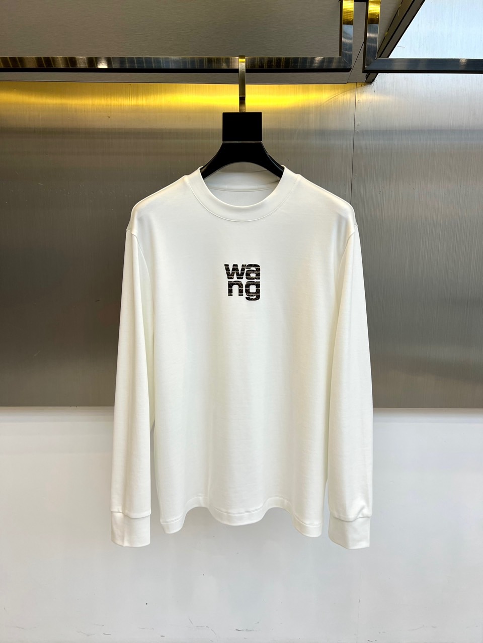 NO:599948,Alexander  W Alexander Wang, 2025 autumn and winter new modal long-sleeved T-shirt, interprets the modern style of New York. This T-shirt adopts a round neck design and loose tailoring, and outlines a relaxed and moderate silhouette through precise silhouette lines. The body is made of 47 modal  The golden ratio fabric of Er, 47 cotton and 6 spandex not only retains the skin-friendly breathability of cotton, but also gives a velvety soft drape feeling through modal, and the spandex component provides just the right elasticity and flexibility. The chest is decorated with the iconic 'wa'  ng' black letter logo, using simple fonts to show the brand's unique design language. The overall design elevates basic items to a high-end fashion level. Whether worn alone with jeans to create a street style, or layered with suits and leather jackets as an inner wear, it can easily create an urban style that is both casual and sophisticated, becoming an indispensable universal item in the autumn and winter wardrobe. 48-56 (model is 173, 143 pounds, upper body size 50),, alexander  wang,jeans,tees,t-shirt,leather jacket,business suit,gold,alexander wang19860909Alexander W亚历山大王、2025秋冬新品莫代尔长袖T恤,演绎纽约摩登风尚.这款T恤采用圆领设计与宽松剪裁,通过精准的版型线条勾勒出松弛有度的轮廓.衣身选用47莫代尔、47棉与6氨纶的黄金比例面料,既保留棉质的亲肤透气性,又通过莫代尔赋予丝绒般柔软垂坠感,氨纶成分则提供恰到好处的弹性灵活度.胸口处饰以标志性的'wang'黑色字母标识,以简约字体展现品牌独特的设计语言.整体设计将基础款单品提升至高级时尚层面,无论是单独搭配牛仔裤演绎街头风格,还是作为内搭与西装、皮衣进行层次叠穿,都能轻松塑造出兼具随性与精致的都市造型,成为秋冬衣橱中不可或缺的万能单品.48-56（模特173,143斤上身50码）,,alexander wang,jeans,tees，t-shirt,leather jacket,business suit,gold,alexander wang,Men's clothing