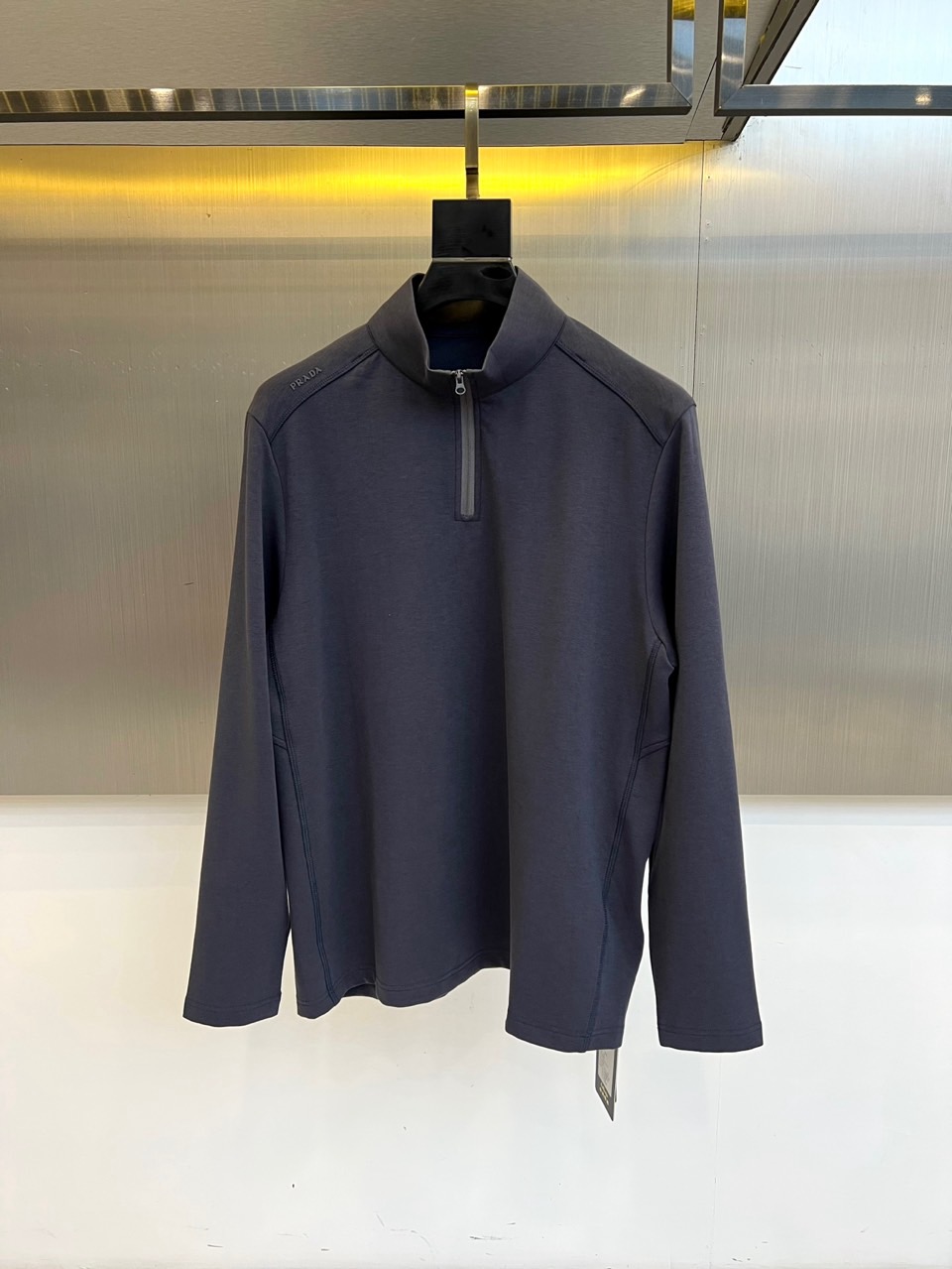 NO:599925,Prad, 2025 autumn and winter new product PRADA technology air layer long-sleeved top. It adopts innovative air layer structure technology, and the fabric ingredients are scientifically matched. 30.1 polyester fiber provides a stiff frame, 28.6 lyocell fiber provides a silky drape, 28.6 cotton ensures skin-friendly breathability, and 12.7 spandex enhances four-way elasticity. The stand-up collar half-zip design is equipped with a smooth zipper system, and the left chest is embellished with the brand's iconic embossed logo.  Combined with Cornelli's dual-effect smart heating technology, the fiber forms a temperature-locking layer through a nanogap structure, converting light energy into heat energy, and has long-lasting elastic recovery and anti-wrinkle properties. It can be worn alone with formal pants for business casual, or can be worn with a coat to create a winter layered look. Interpretation of the design philosophy of integrating smart technology with Italian aesthetics. M-4XL (model 173, 143 pounds, upper body size L),, prada, prada, alexander wangprada19860909Prad普拉、2025秋冬新品 PRADA科技空气层长袖上衣.采用创新空气层结构技术,面料成分经过科学配比30.1聚酯纤维提供挺括骨架,28.6莱赛尔纤维赋予丝滑垂坠感,28.6棉质保证亲肤透气性,12.7氨纶增强四向弹性.立领半拉链设计搭配顺滑拉链系统,左胸点缀品牌标志性压印标识. 结合科耐丽双效智暖科技,纤维通过纳米间隙结构形成锁温层,将光能转化为热能,同时具备持久的弹性回复性与抗皱特性.既可单穿搭配正装裤演绎商务休闲,也可外搭大衣打造冬日层次造型.诠释将智能科技与意式美学相融合的设计哲学.M-4XL（模特173,143斤上身L码）,,prada,prada,alexander wang,Men's clothing