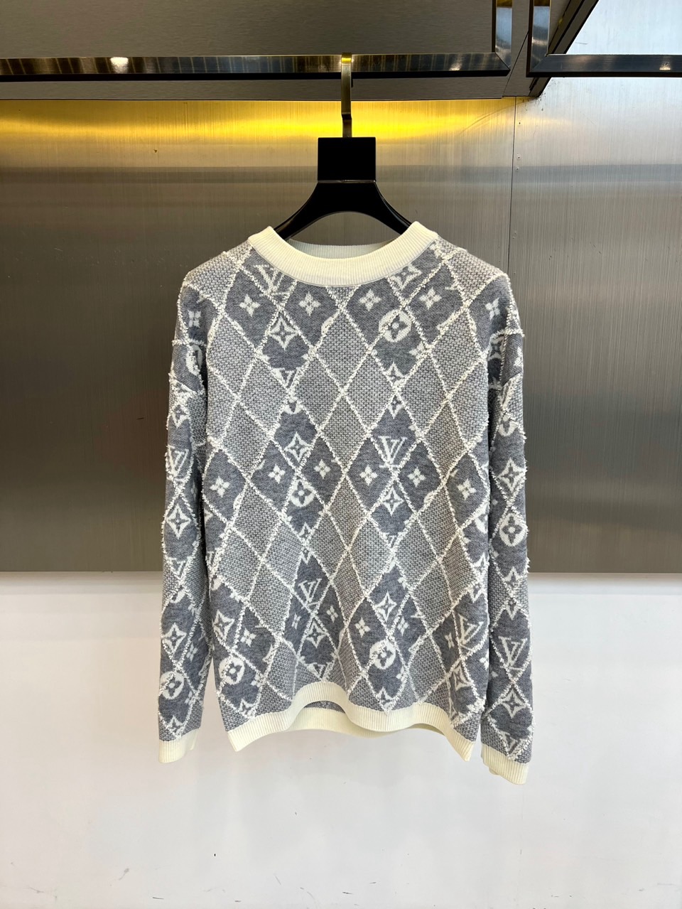 NO:599949,1v Vuitton, the new 2025 autumn and winter gray rhombus knitted sweater, reshapes the classic knitted aesthetics with the brand's iconic Monogram presbyopia pattern. The style adopts a slim round neck design, the body is covered with three-dimensional rhombus patterns, intertwined with the faint LV letter print, and the cuffs and hem are ribbed to ensure a crisp fit. The fabric is made of worsted cotton, and the gray and white color combination not only retains the brand's genes but also adds a modern feel.  Its design combines traditional knitting techniques with street elements. The diamond pattern enhances the visual layering. It can be paired with a leather skirt to show a modern temperament, or it can be paired with straight jeans for a casual fashion. From the opening of an art exhibition to a city stroll, this sweater has a low-key presbyopic pattern and a clever combination of diamond texture. It has become a fashion carrier that connects century-old heritage and contemporary life, interpreting Louis  Vuitton's innovative interpretation of classic items. 48-56 (model is 173,143 pounds and 50 upper body,,louis vuitton,louis vuitton,skirts,jeans,alexander wang198609091v威登、2025秋冬新品灰色菱格纹针织衫,以品牌标志性Monogram老花图案重塑经典针织美学.款式采用修身圆领设计,衣身满铺立体菱格纹路,交织着若隐若现的LV字母印花,袖口与下摆采用罗纹收边工艺确保版型挺括.面料选用精纺棉质材质,灰白配色既保留品牌基因又增添现代感. 其设计将传统针织工艺与街头元素相融合,菱格纹路增强视觉层次感,可搭配皮革半裙展现摩登气质,亦可与直筒牛仔裤碰撞出休闲时尚.从艺术展开幕到都市漫步,这款针织衫以低调的老花图案与菱格纹理的巧妙结合,成为连接百年传承与当代生活的时尚载体,诠释Louis Vuitton对经典单品的创新演绎.48-56（模特173,143斤上身50吗,,louis vuitton,louis vuitton,skirts,jeans,alexander wang,Men's clothing