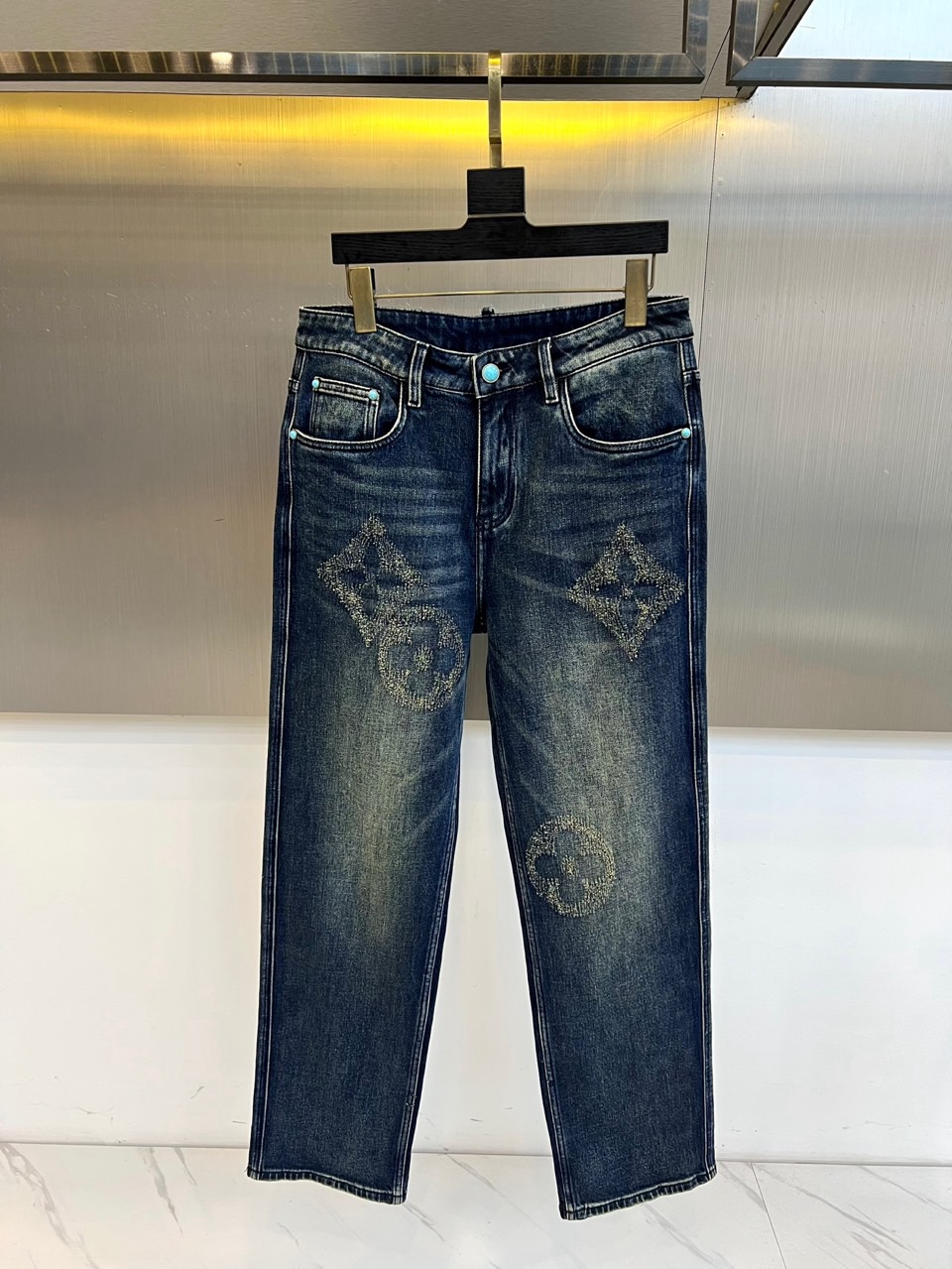 NO:599929,1v Vuitton, 2025 autumn and winter new distressed pattern jeans, reshape the retro denim aesthetics with a classic five-pocket style. The dark blue denim base is decorated with iconic metal rivets, and the waistband is embellished with blue button details. The front of the trousers is paved with the brand's classic presbyopia pattern and geometric circular patterns, all made of precision inlaid brilliant diamonds. The fabric is made of cotton denim, which uses a special distressing process to present natural texture and diamonds.  The decorative part uses hand-inlaid technology to ensure firmness. Its design combines street denim with advanced customization craftsmanship. It can be paired with a simple top to highlight the visual focus of trousers, and can also collide with luxurious fur to create a mix and match tension. From fashion parties to high-end casual occasions, this pair of jeans has become an iconic item that interprets LV's cross-border aesthetics with its subversive material dialogue and exquisite craftsmanship. 29-36 (35), louis  vuitton,jeans,alexander wang198609091v威登、2025秋冬新品磨破图案牛仔裤,以经典五袋款型重塑复古牛仔美学.深蓝色牛仔布基底搭配标志性金属铆钉装饰,裤腰处点缀蓝色纽扣细节.裤身正面铺陈品牌经典老花图案与几何圆形纹样,全部采用精密镶嵌的璀璨钻饰构成,面料选用棉质牛仔布,通过特殊做旧工艺呈现自然纹理,钻饰部分采用手工镶嵌技术确保牢固度.其设计将街头牛仔与高级定制工艺相融合,可搭配简约上衣突出裤装视觉焦点,亦能与奢华皮草碰撞出混搭张力.从时尚派对到高端休闲场合,这款牛仔裤以颠覆性的材质对话与精湛工艺,成为诠释LV跨界美学的标志性单品.29-36（有35）,,louis vuitton,jeans,alexander wang,Men's clothing