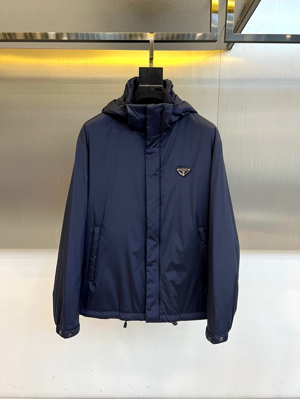 NO:599935,PRAD, the new plaid hooded cotton jacket for autumn and winter 2025, adopts a hooded design with a smooth zipper closure system. The left chest is embellished with the brand's iconic triangular enamel logo. The body is formed with a geometric plaid texture through precise quilting technology. The diagonal pockets on both sides are integrated into three-dimensional tailoring, and the cuffs are equipped with pressable buttons to enhance practicality. The fabric is made of nylon material to ensure windproof performance, the lining is polyester fiber, and the filling is made of high-quality polyester fiber thermal insulation material.  Its design combines classic plaid genes with practical functions. It can be paired with casual trousers to create an urban look, or it can be paired with formal trousers to create a business casual style. From commuting to weekend socializing, the brand recognition of the precise shape and triangular logo has become a vehicle for connecting Italian craftsmanship and daily wear.  Body. Strictly implement the GB/T2662-2017 standard and Category C safety regulations, interpreting PRADA's in-depth exploration of texture and practicality. 48-56 (model 173, 143 pounds upper body size 50),, prada, prada, jackets  & coats,hats,alexander wang19860909PRAD普拉、2025秋冬新品格纹连帽棉服外套,款式采用连帽设计搭配顺滑拉链开合系统,左胸点缀品牌标志性三角形珐琅徽标,衣身通过精准的绗缝工艺形成几何格纹肌理.两侧斜插口袋融入立体剪裁,袖口配备可按压式纽扣增强实用性.面料采用锦纶材质确保防风性能,里料为聚酯纤维,填充物采用优质聚酯纤维保暖材料. 其设计将经典格纹基因与实用功能相融合,可搭配休闲长裤打造都市造型,亦可与正装裤碰撞出商务休闲风范.从通勤出行到周末社交,精准版型与三角形徽标的品牌辨识度,成为连接意式工艺与日常着装的载体.严格执行GB/T2662-2017标准与C类安全规范,诠释PRADA对质感与实穿性的深度探索.48-56（模特173,143斤上身50码）,,prada,prada,jackets & coats,hats,alexander wang,Men's clothing