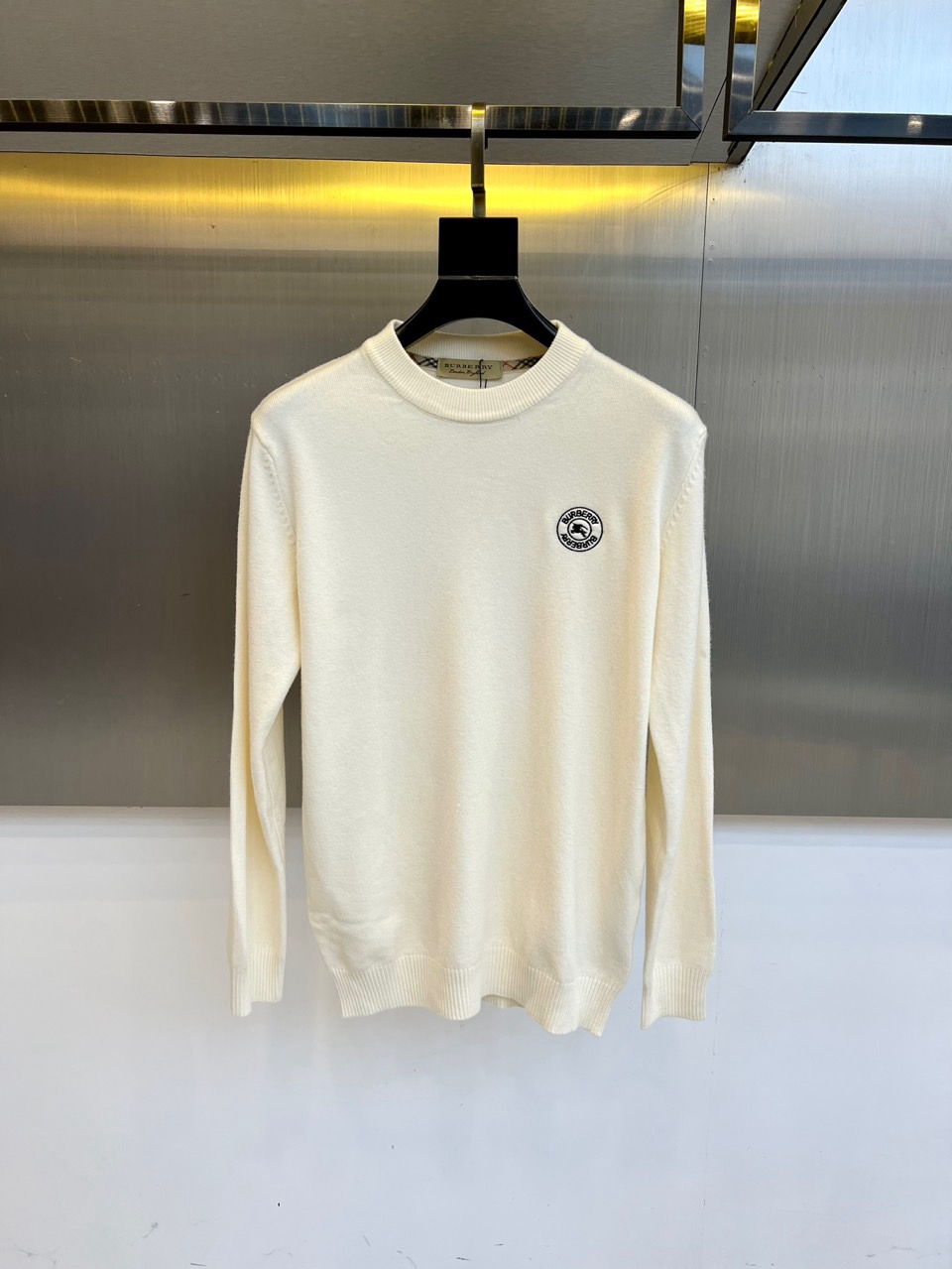 NO:600852,Burberry, 2025 autumn and winter new round neck sweater, interprets British elegant aesthetics with minimalist design. The style adopts a classic round neck silhouette, with the brand's iconic black circular logo embellished on the left chest. The brand logo and founding year are finely embossed on the badge, highlighting a century-old heritage. The fabric is strictly made of wool, and the Italian manufacturing process ensures a delicate and soft knitted texture and excellent shape retention. The label clearly indicates the professional care guide. Do not wash, do not chlorine bleach, do not tumble dry, it is recommended to iron at low temperature and professional gentle dry cleaning.  Its three-dimensional tailoring optimizes body lines through precise proportions, and the wool material brings a comfortable and skin-friendly wearing experience. It can be worn alone with suit pants to show a business casual style, or it can be combined with a skirt to create an elegant daily look. From important meetings to social occasions, this sweater combines the natural texture of pure wool with the ingenious craftsmanship of the logo details.  As a fashion carrier that connects brand heritage and modern life, it interprets Burberry's contemporary reconstruction of classic items. M-4XL (model weighs 173,143 pounds, upper body size L),,burberry,burberry,skirts,sweaters,business  suit,alexander wang19860909Bur巴宝莉、2025秋冬新作圆领毛衣,以极简设计诠释英伦优雅美学.款式采用经典圆领廓形,左胸点缀品牌标志性黑色圆形徽标,徽章上精细压印品牌标识与创立年份,彰显百年传承.面料严格选用羊毛材质,意大利制造工艺确保细腻柔软的针织纹理与卓越版型保持度.标签明确标注专业养护指南不可水洗、不可氯漂、不可转筒干燥,建议低温熨烫与专业缓和干洗. 其立体剪裁通过精准比例优化身形线条,羊毛材质带来亲肤舒适的穿着体验.可单独搭配西装裤展现商务休闲风范,亦可与半裙组合营造优雅日常造型.从重要会晤到社交场合,这款毛衣以纯羊毛的天然质感与徽标细节的匠心工艺,成为连接品牌遗产与现代生活的时尚载体,诠释Burberry对经典单品的当代重构.M-4XL（模特173,143斤上身L码）,,burberry,burberry,skirts,sweaters,business suit,alexander wang,Men's clothing