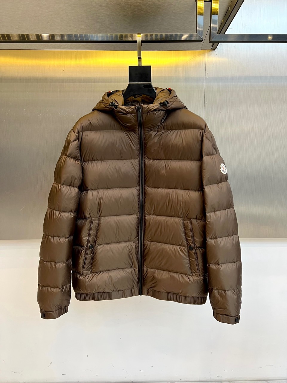 NO:600854,Mon (goose down), the new down jacket for autumn and winter 2025, this hooded down jacket adopts a classic horizontal pressure line design to form a three-dimensional checkered shape, which not only enhances the sense of layering, but also effectively prevents uneven distribution of down material. The edge of the hat is equipped with an adjustable drawstring, and the hem is slim-fitting. The snap button pockets on both sides are both practical and beautiful. The classic round logo on the left sleeve is a low-key way to highlight the brand genes.  The fabric uses a technological combination of 83 polyamide and 17 elastic fibers, which not only maintains the wear-resistant properties of nylon, but also gives clothing moderate elasticity. The core filling strictly follows EU EN12934, American standards and Japanese JIS L  1903:2011 has three major international certifications. It uses a golden ratio of 90% high-quality goose down and 10% feathers to ensure that the fluffiness and warmth retention performance reach professional levels. In the details, you can see the ingenious black smooth zipper running through the front, and the internal label clearly indicates the animal-derived ingredients, reflecting the insistence on material transparency.  This down jacket perfectly combines functional wear with urban aesthetics. Whether it is commuting or outdoor activities, it can provide a light and long-lasting warmth experience in the cold season, becoming a quality choice for tasteful people's autumn and winter wardrobe. Sizes 1-5 (model 173,143 pounds upper body size 2), Moncler, down jacket, gold, hats, alexander wang19860909Mon蒙口（鹅绒）、2025秋冬新品羽绒服,这款连帽羽绒服采用经典横向压线设计,形成立体方格造型,不仅增强了层次感,更有效防止绒料分布不均.帽子边缘配有可调节抽绳,下摆则采用修身剪裁,两侧按扣口袋兼顾实用性与美观度.左袖上的经典圆形标识低调彰显品牌基因. 面料采用83聚酰胺与17弹性纤维的科技组合,既保持尼龙的耐磨特性,又赋予衣物适度弹性.核心填充严格遵循欧盟EN12934、美国标准及日本JIS L 1903:2011三大国际认证,选用90高品质鹅绒与10羽毛的黄金配比,确保蓬松度与保暖性能达到专业级水准.细节处可见匠心黑色顺滑拉链贯穿前襟,内部标签明确标注动物源性成分,体现对材质透明度的坚持. 这款羽绒服将功能性穿着与都市美学完美融合,无论是通勤出行还是户外活动,都能在寒冷季节提供轻盈而持久的保暖体验,成为品味人士秋冬衣橱的质感之选.1-5码（模特173,143斤上身2码）,,Moncler,down jacket,gold,hats,alexander wang,Men's clothing