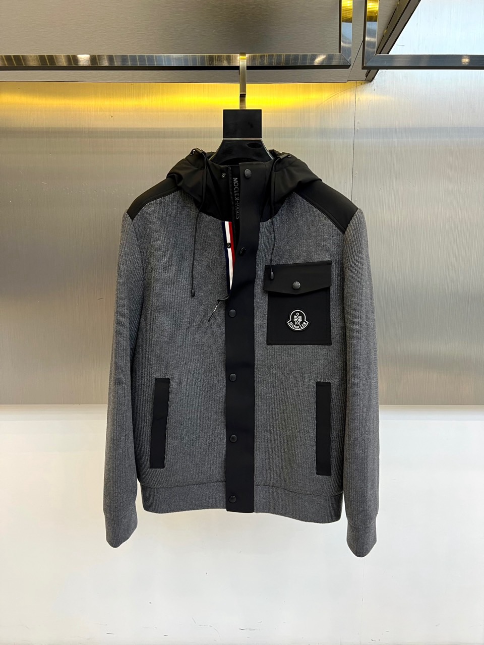 NO:600856,Mon (high-end customization), 2025 autumn and winter new products | Mongolian knitted hooded down jacket.  This dark gray down jacket has a hooded design with an adjustable drawstring. The collar and pockets are spliced with black fabric to form a visual hierarchy. The front is equipped with a row of black button closure systems, and the brand's signature patch pocket is set on the left chest. The long pockets on both sides are diagonally inserted for practical functions. The fabric contains 40 nylon, 30 acrylic and 24 polyester fibers, and the lining is nylon, filled with 85 down content white duck down.  Three-dimensional tailoring combined with ribbing technology ensures wind resistance and warmth. The dark gray main tone is suitable for urban and outdoor scenes. It can be paired with casual pants to create a winter style, or for daily protection in slightly cold weather. Through the combination of splicing design and professional filling technology, it interprets the brand's design philosophy of integrating practical functions with fashion aesthetics. 48-56 (model 173, 143 pounds, upper body size 50), Moncler, down jacket, hats, alexander wang19860909Mon蒙口（高端定制）、2025秋冬新品 | 蒙口针织连帽羽绒服. 这款深灰色羽绒服采用连帽设计搭配可调节抽绳,领口与袋口以黑色面料拼接形成视觉层次.前襟配置一排黑色纽扣开合系统,左胸设品牌标志性贴袋,两侧斜插长袋兼顾实用功能.面料含40锦纶、30腈纶与24聚酯纤维,里料为锦纶,填充85绒子含量白鸭绒 立体剪裁配合罗纹收边工艺,确保防风保暖性.深灰主调适配都市与户外多场景,既可搭配休闲裤打造冬日型格,也能应对微寒天气的日常防护.通过拼接设计与专业填充技术的结合,诠释品牌将实用功能与时尚美学相融的设计哲学.48-56（模特173,143斤上身50码）,,Moncler,down jacket,hats,alexander wang,Men's clothing