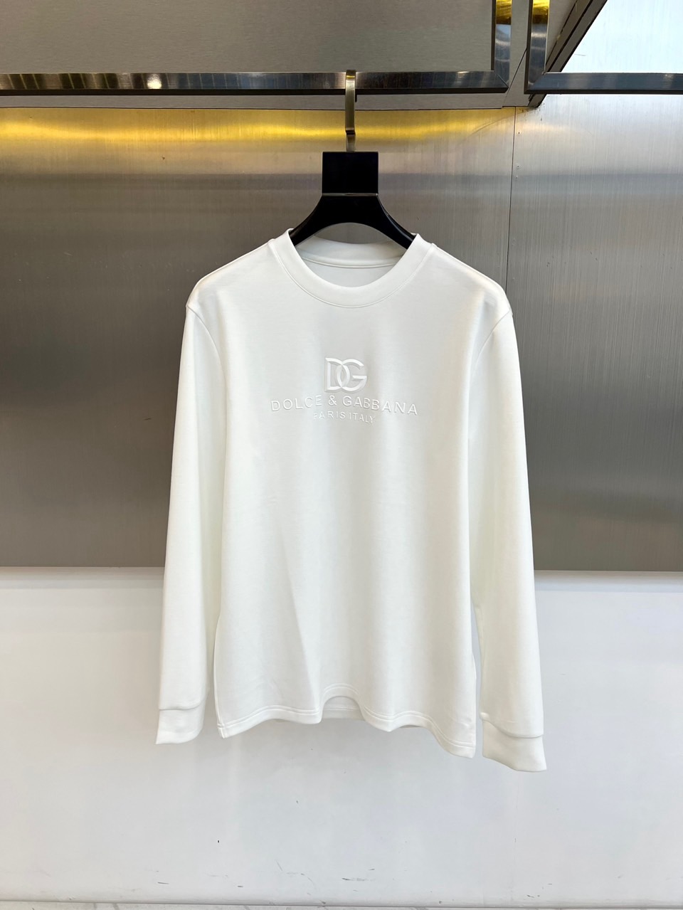 NO:600849,DG Dolce & Gabbana, 2025 autumn and winter new DG style minimalist long-sleeved top. This long-sleeved top adopts a classic round neck design, with the brand's iconic 'DG' letter logo on the front and 'DOLCE&GABBANA PARIS' underneath.  ITALY' words, using simple embroidery technology to show a low-key luxury. The fabrics are made of 29.5 modal, 12.5 cotton, 6 spandex, 29.5 viscose fiber and 22.5 polyester fiber in a scientific ratio. The modal component gives a silky touch, the cotton ensures breathability, and the spandex provides moderate elasticity.  The tone continues the elegant gene of the brand, which can be worn alone with casual pants to create an urban minimalist style, or as an inner layer with a suit jacket for a business casual look. Through the combination of iconic elements and comfortable fabrics, it interprets DG's design philosophy of integrating Italian aesthetics into daily wear. 48-56 (model 173,143 pounds, upper body size 50),,Dolce&Gabbana,Dolce&Gabbana,jackets & coats, business suit,alexander wang19860909DG杜嘉班纳、2025秋冬新品DG风格极简长袖上衣. 这款长袖上衣采用经典圆领设计,衣身正面饰有品牌标志性“DG”字母标识,下方搭配“DOLCE&GABBANA PARIS ITALY”字样,以简约刺绣工艺展现低调奢华感.面料选用29.5莫代尔、12.5棉、6氨纶、29.5粘纤与22.5聚酯纤维科学配比,莫代尔成分赋予丝滑触感,棉质保证透气性,氨纶提供适度弹性. 基调延续品牌优雅基因,既可单穿搭配休闲裤打造都市极简风,也可作为内搭配合西装外套演绎商务休闲造型.通过标志性元素与舒适面料的结合,诠释DG将意式美学融入日常穿着的设计哲学.48-56（模特173,143斤上身50码）,,Dolce&Gabbana,Dolce&Gabbana,jackets & coats,business suit,alexander wang,Men's clothing