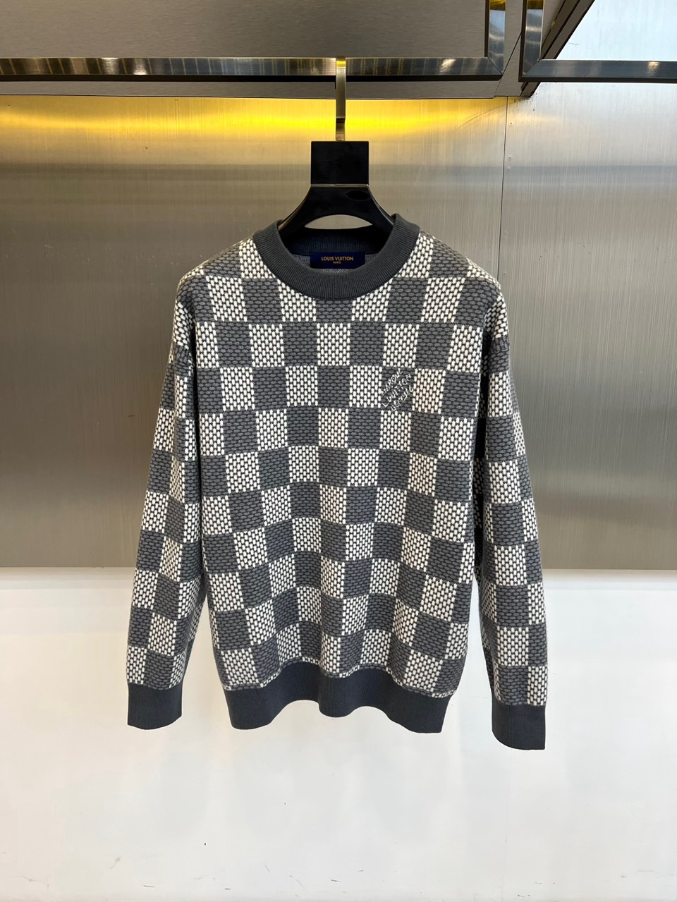 NO:600864,LOUIS VUITTON  The new 2025 autumn and winter knitted sweaters use the brand's iconic gray and white checkerboard pattern to interpret modern and elegant aesthetics. The style adopts a classic round neck design, and the neckline, cuffs and hem are made of dark gray ribbing technology, forming a delicate transition with the body plaid. The fabric is made of worsted cotton, and the three-dimensional weaving process presents a concave and convex geometric texture to ensure a soft and skin-friendly wearing experience. Its design combines the brand's classic genes with practicality  It can be combined with casual pants of the same color to enhance the overall look, or it can be combined with denim items to create a fun mix and match. From business casual to daily socializing, this sweater has the eternal charm of checkerboard elements and precise tailoring, becoming a fashion carrier that connects brand heritage and contemporary life, interpreting Louis Vuitton's contemporary reconstruction of classic items. 48-56 (model is 173, 143 pounds, upper body 50, Louis Vuitton  vuitton,louis vuitton,alexander wang19860909LOUIS VUITTON 2025秋冬新品针织衫,以品牌标志性灰白棋盘格图案演绎现代优雅美学.款式采用经典圆领设计,领口、袖口及下摆采用深灰色罗纹收边工艺,与衣身格纹形成细腻层次过渡.面料选用精纺棉质材质,通过立体编织工艺呈现凹凸有致的几何纹理,确保柔软亲肤的穿着体验.其设计将品牌经典基因与实穿主义相融合,可搭配同色系休闲裤强化整体感,亦可与牛仔单品碰撞出混搭趣味.从商务休闲到日常社交,这款针织衫以棋盘格元素的永恒魅力与精准剪裁,成为连接品牌传承与当代生活的时尚载体,诠释路易威登对经典单品的当代重构.48-56（模特173,143斤上身50吗,,louis vuitton,louis vuitton,alexander wang,Men's clothing