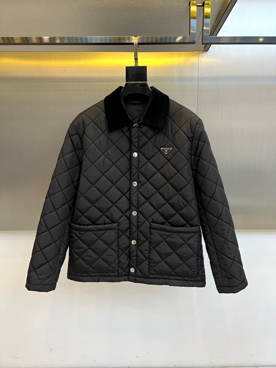 p430 Prad普拉达、2025秋冬新品棉服以经典菱格绗缝工艺重塑都市保暖美学。这款棉服采用立体翻领设计,内衬选用丝绒质感面料提升穿着舒适度。衣襟配备哑光金属按扣闭合系统,左侧胸口点缀标志性珐琅三角徽标,袖口采用罗纹收口设计防风保暖。填充高品质环保棉絮通过规整的菱形绗缝固定,既确保保暖性能又形成独特的立体纹理。
其剪裁融合修身与宽松的平衡感,双侧斜插口袋兼顾实用功能与线条流畅度。黑色面料表面呈现细微肌理变化,在光线折射下展现低调奢华感。从商务通勤到周末休闲,这款棉服能完美适配多种场合,既可搭配正装展现干练气质,也能结合休闲服饰营造轻松氛围。
细节处体现意式匠心,如精准的走线工艺与品牌标识的细腻铸造。它将实用主义与高级时装语言相融合,通过极简设计诠释永恒经典的冬季造型,成为追求品质生活的都市人士衣橱中不可或缺的时尚单品。48-56(模特173,143斤上身50码)