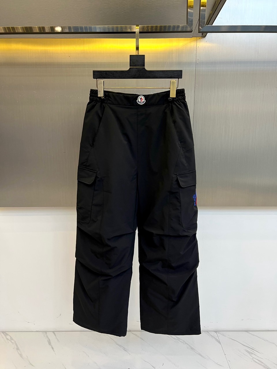 NO:608669,Mon Mengkou, the new outdoor down pants for autumn and winter 2025, uses a pure black color to interpret the functional aesthetics of mountain style. This down pants adopts a loose straight fit design, equipped with an adjustable elastic band and black plastic fasteners at the waist, and large work style pockets on both sides that combine practical function and style. The side of the right leg is decorated with a colorful brand badge, injecting vitality into the calm black tone. The fabric and lining are made of polyester fiber, filled with high-quality duck down with a 90% down content, ensuring light and warm performance.  Its design perfectly combines outdoor protection with urban fashion. The three-dimensional tailoring reserves ample space for movement, and the cargo pocket design enhances practical performance. Whether it is hiking in the snow or commuting in the city, these down pants can handle a variety of scenes with the iconic quality craftsmanship of Meng Mou. From professional outdoor activities  For daily fashion wear, it not only maintains the warmth of professional down items, but also shows a fashionable attitude through detailed design, becoming a must-have winter item for modern consumers who pursue both function and style. 48-56 (please state your height and weight when placing an order),,Moncler,down  jacket,alexander wang19860909Mon蒙口、2025秋冬新品户外羽绒裤,以纯黑配色演绎山系机能美学.这款羽绒裤采用宽松直筒版型设计,腰部配备可调节松紧带与黑色塑料扣件,两侧工装风大口袋兼顾实用功能与造型感.右腿侧边装饰彩色品牌徽章,为沉稳黑色调注入活力亮点.面料与里料均采用聚酯纤维,填充90绒子含量的优质鸭绒,确保轻盈保暖性能. 其设计将户外防护性与都市时尚感完美融合,立体剪裁预留充足活动空间,工装口袋设计增强实用性能.无论是雪地徒步还是城市通勤,这条羽绒裤都能以蒙口标志性的品质工艺应对多种场景.从专业户外活动到日常潮流穿搭,它既保持专业羽绒单品的保暖实力,又通过细节设计展现时尚态度,成为追求功能与风格兼具的现代消费者冬季必备单品.48-56（下单请报身高体重）,,Moncler,down jacket,alexander wang,Men's clothing